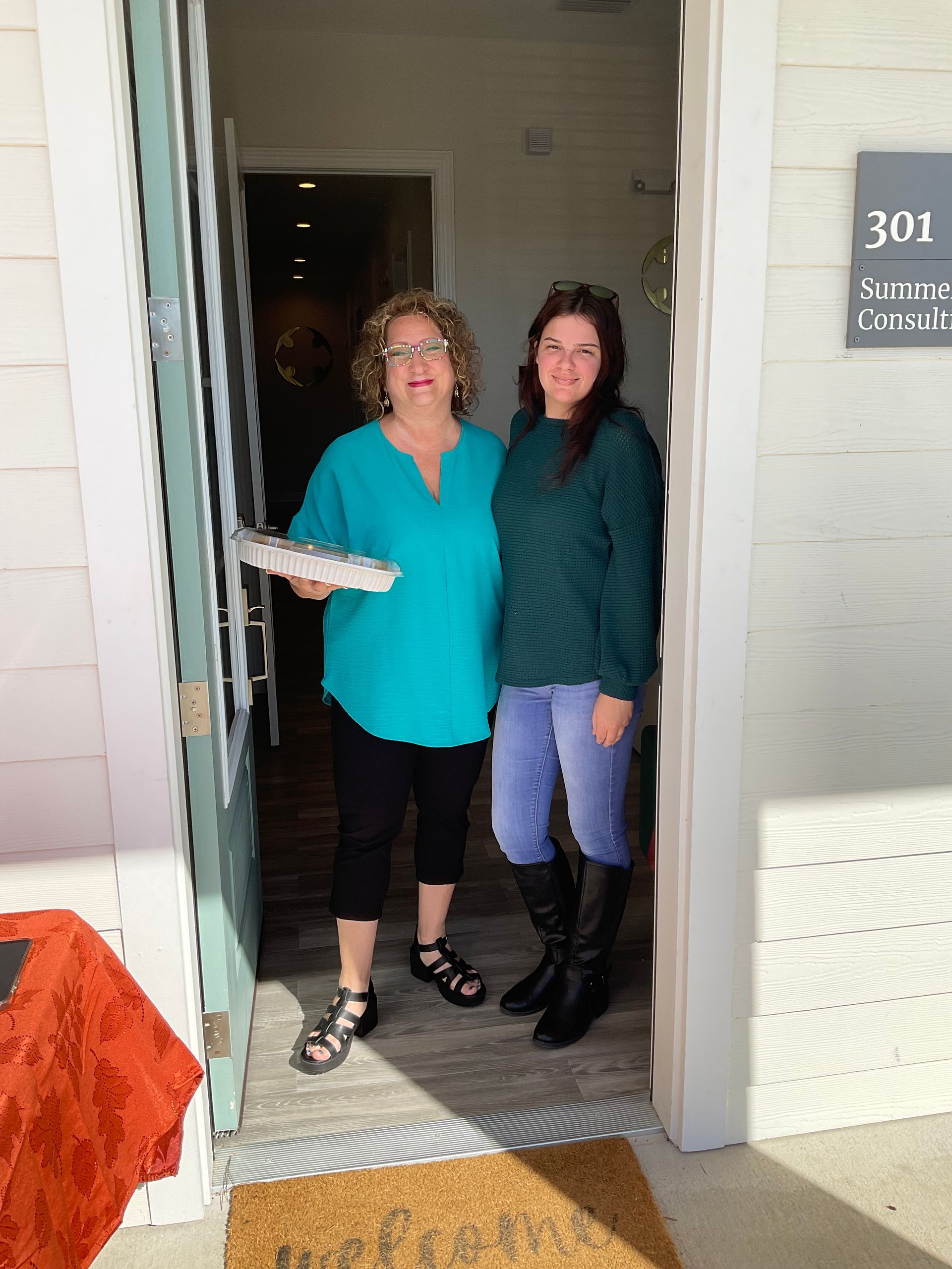 Two women are standing in the doorway of a house.