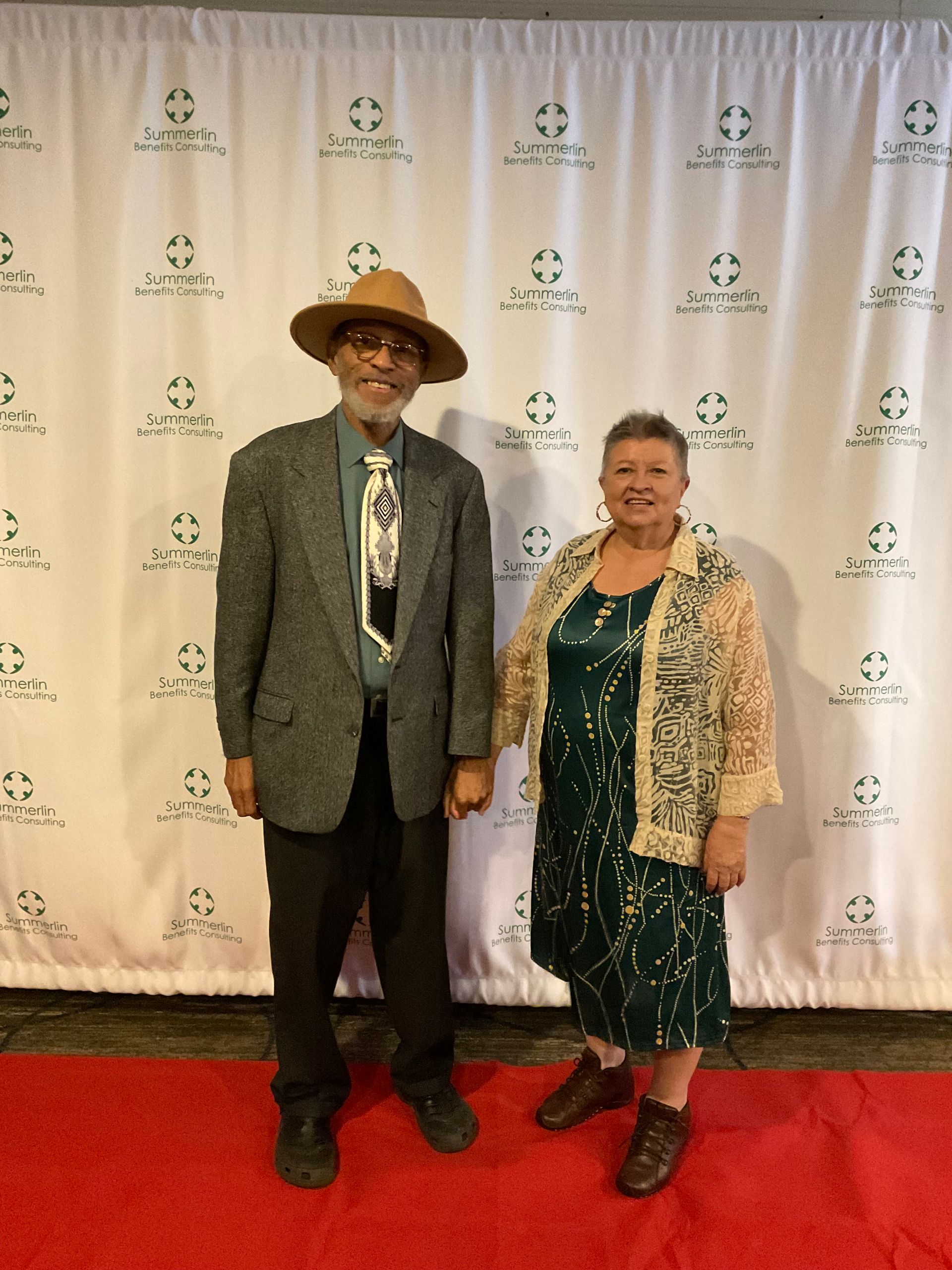 A man and a woman are standing on a red carpet