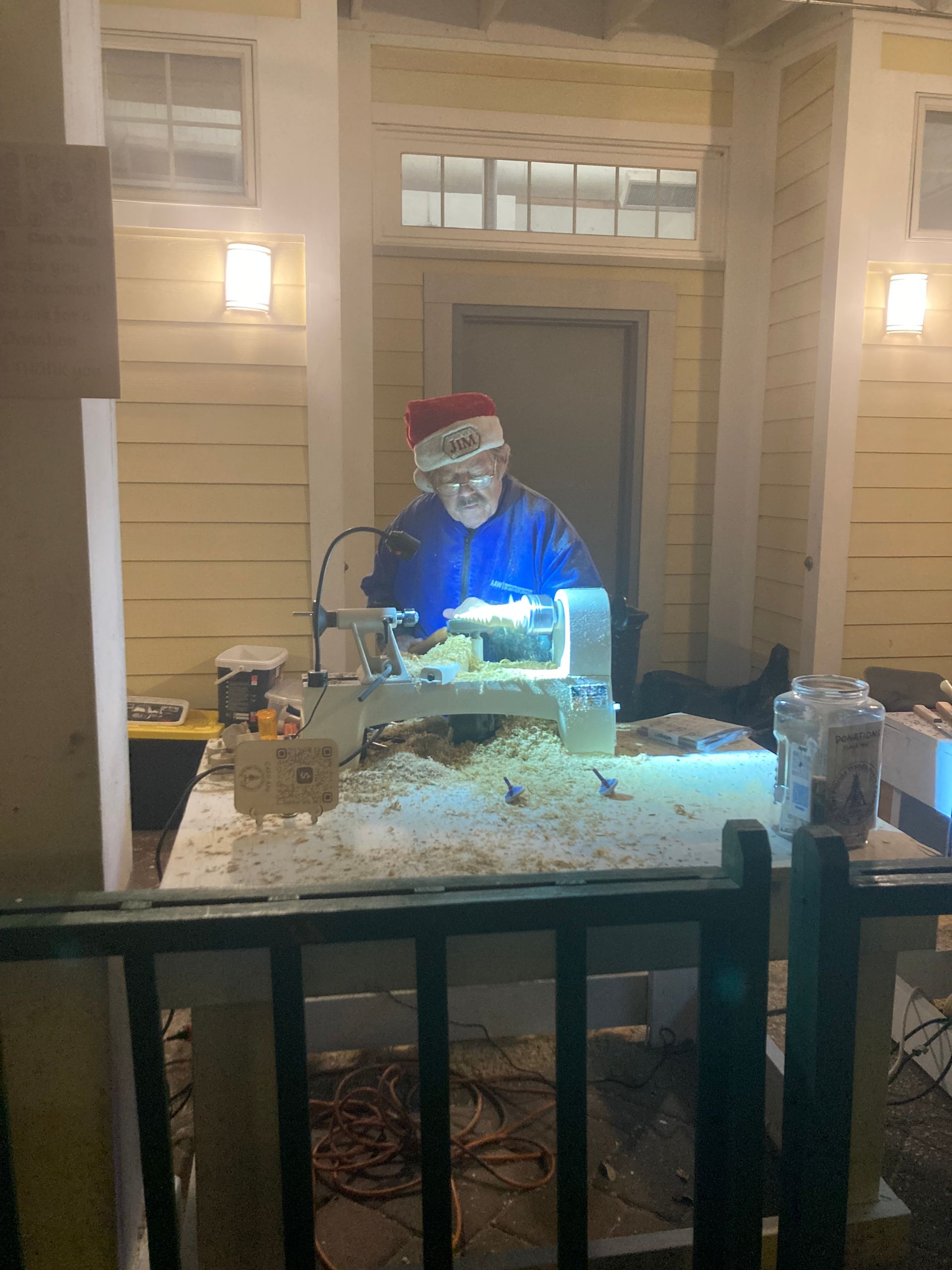 Santa Claus figure lit in blue at a snowy outdoor display on a porch at night