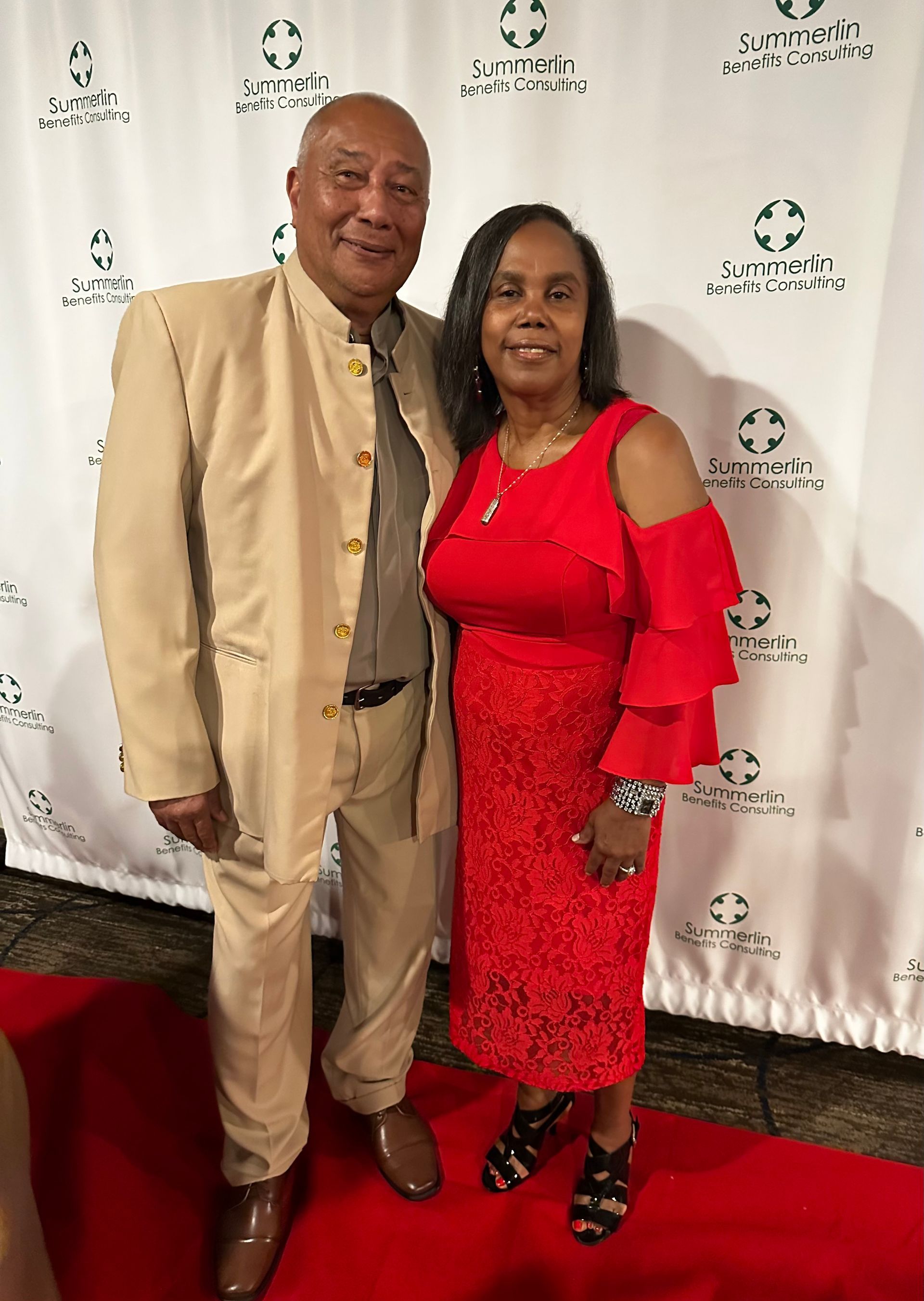 A man and a woman are posing for a picture on a red carpet.