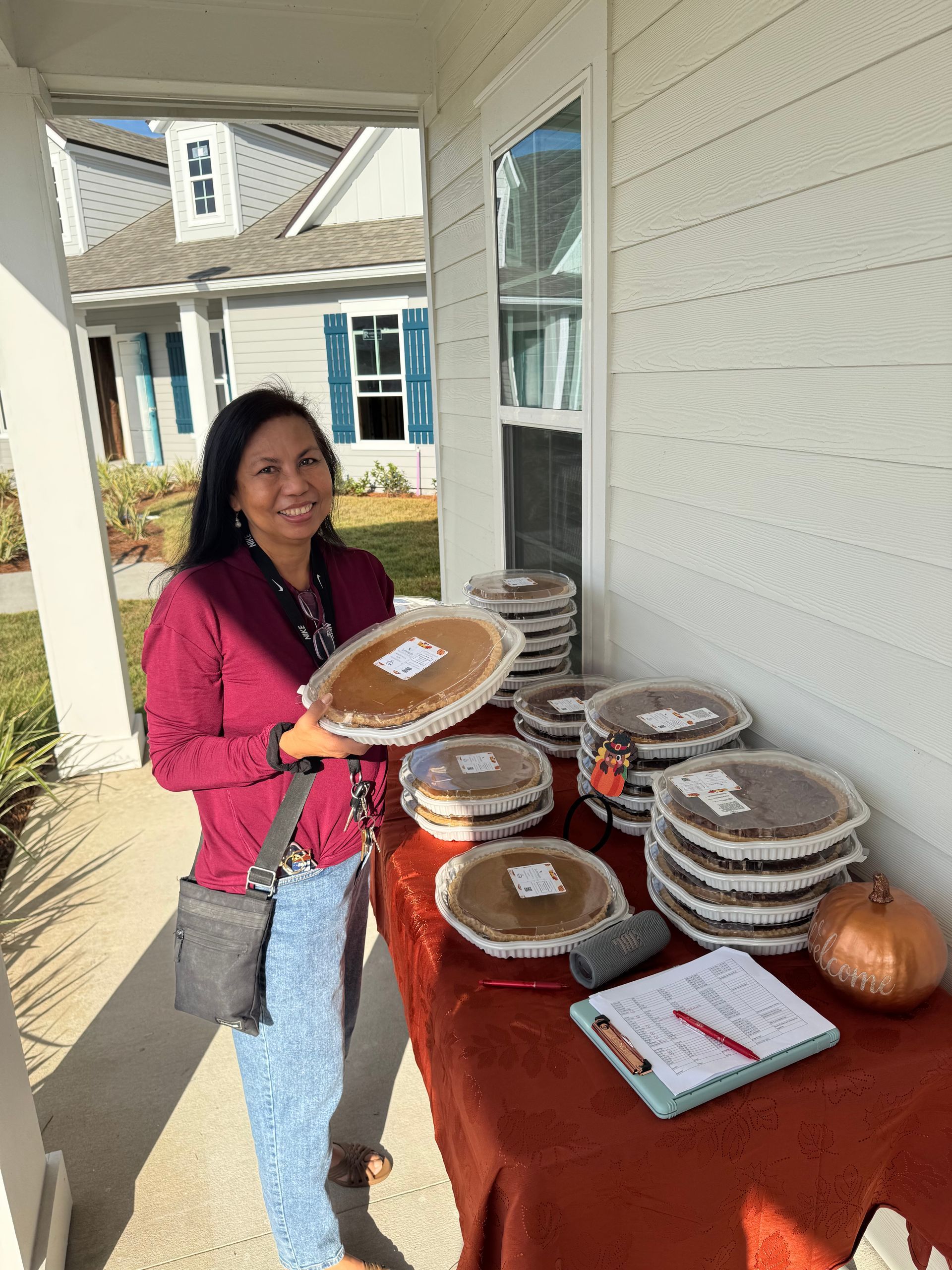 Woman stands by a table of covered dishes and a sign outside a building.