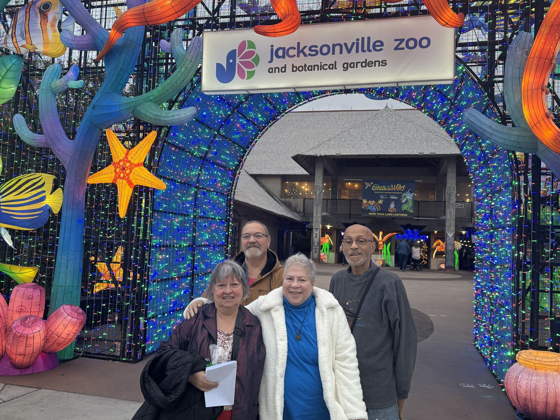 Four people posing at the Jacksonville Zoo entrance under colorful sea-creature decorations.