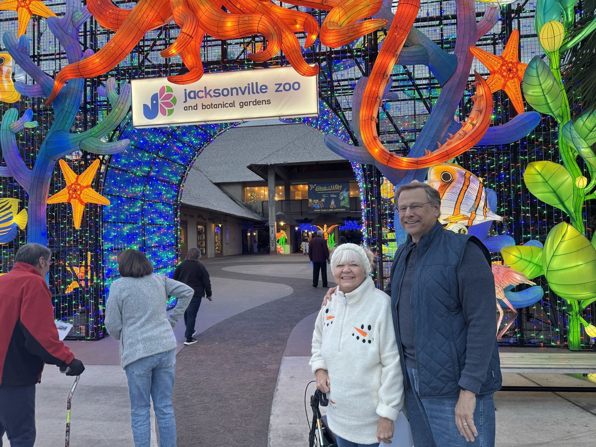 Visitors posing at the Jacksonville Zoo entrance under a colorful butterfly light display