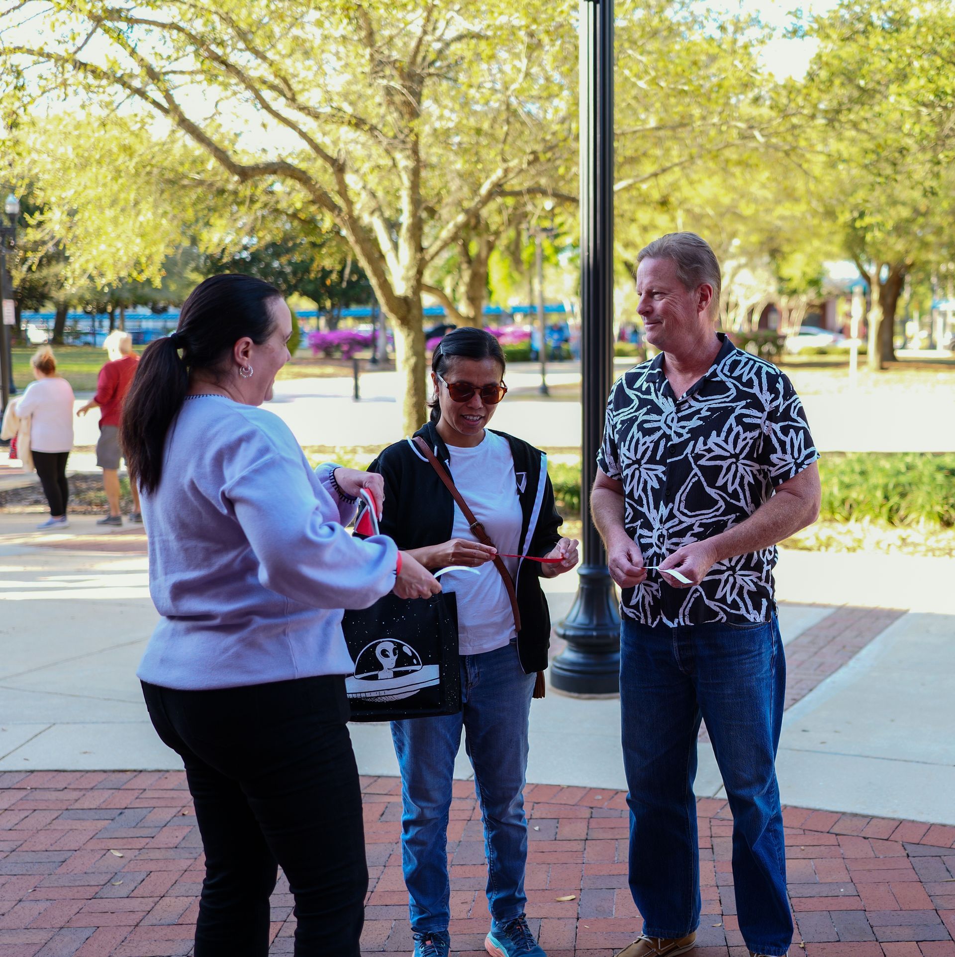 A group of people standing on a sidewalk talking to each other