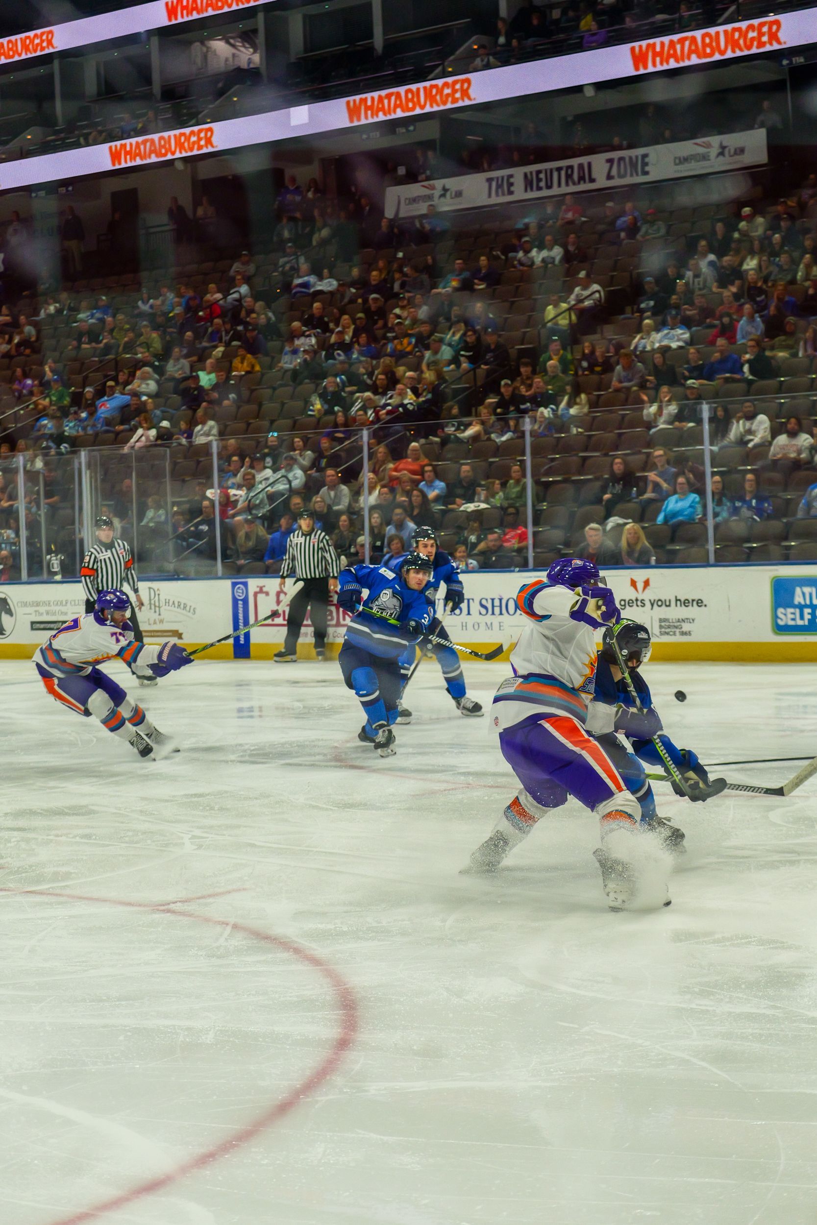 A group of hockey players are playing a game on the ice.