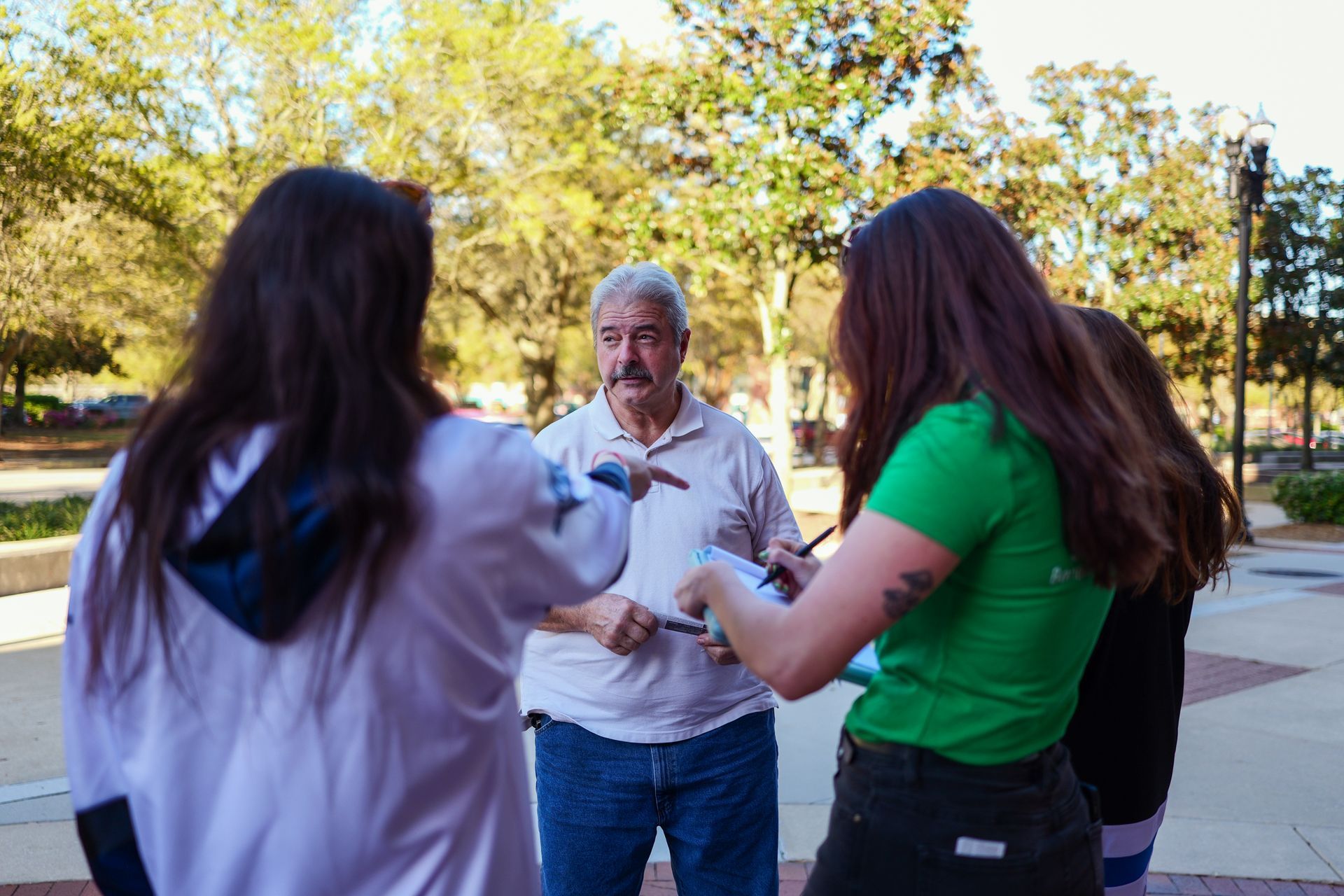 A group of people are standing in a circle talking to each other.