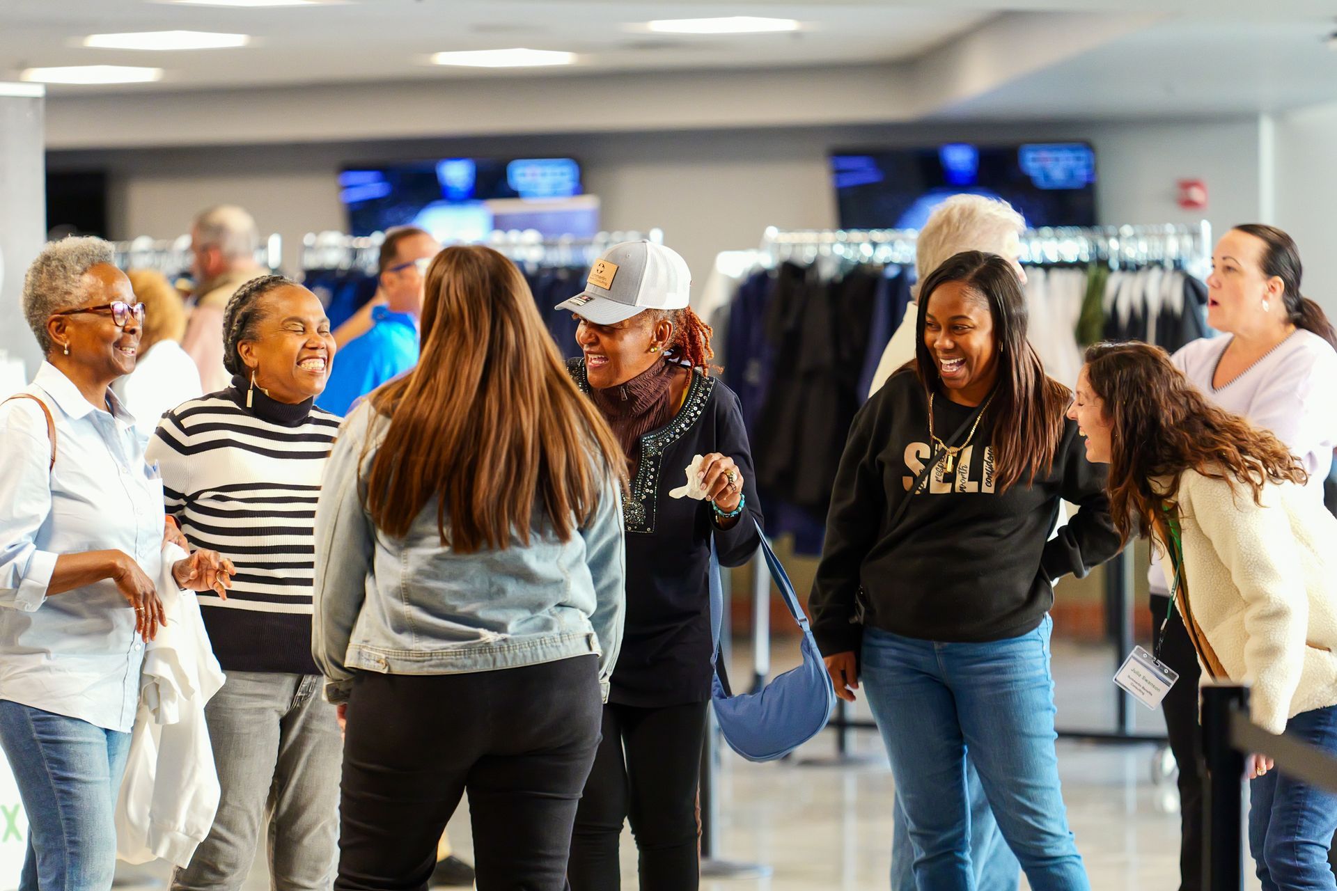 A group of people are standing in a room talking to each other.