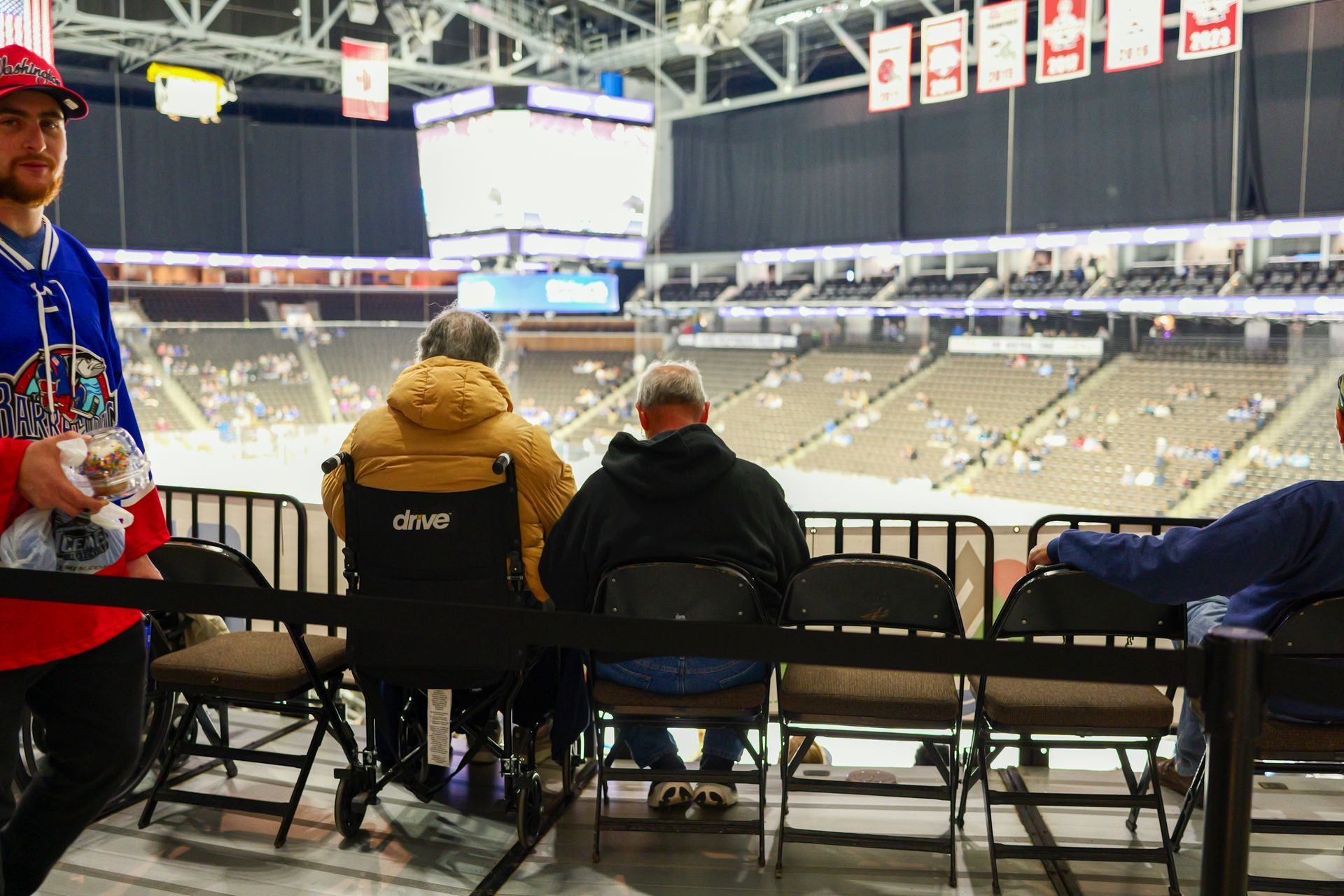 A group of people in wheelchairs are sitting in a stadium watching a hockey game.