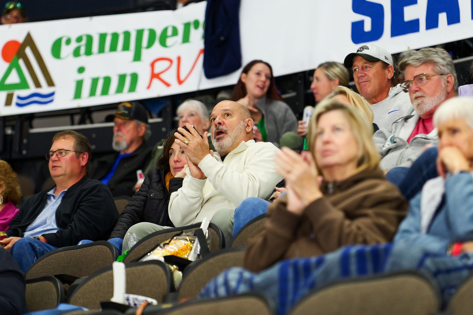 A group of people sitting in a stadium with a banner that says camper inn rv