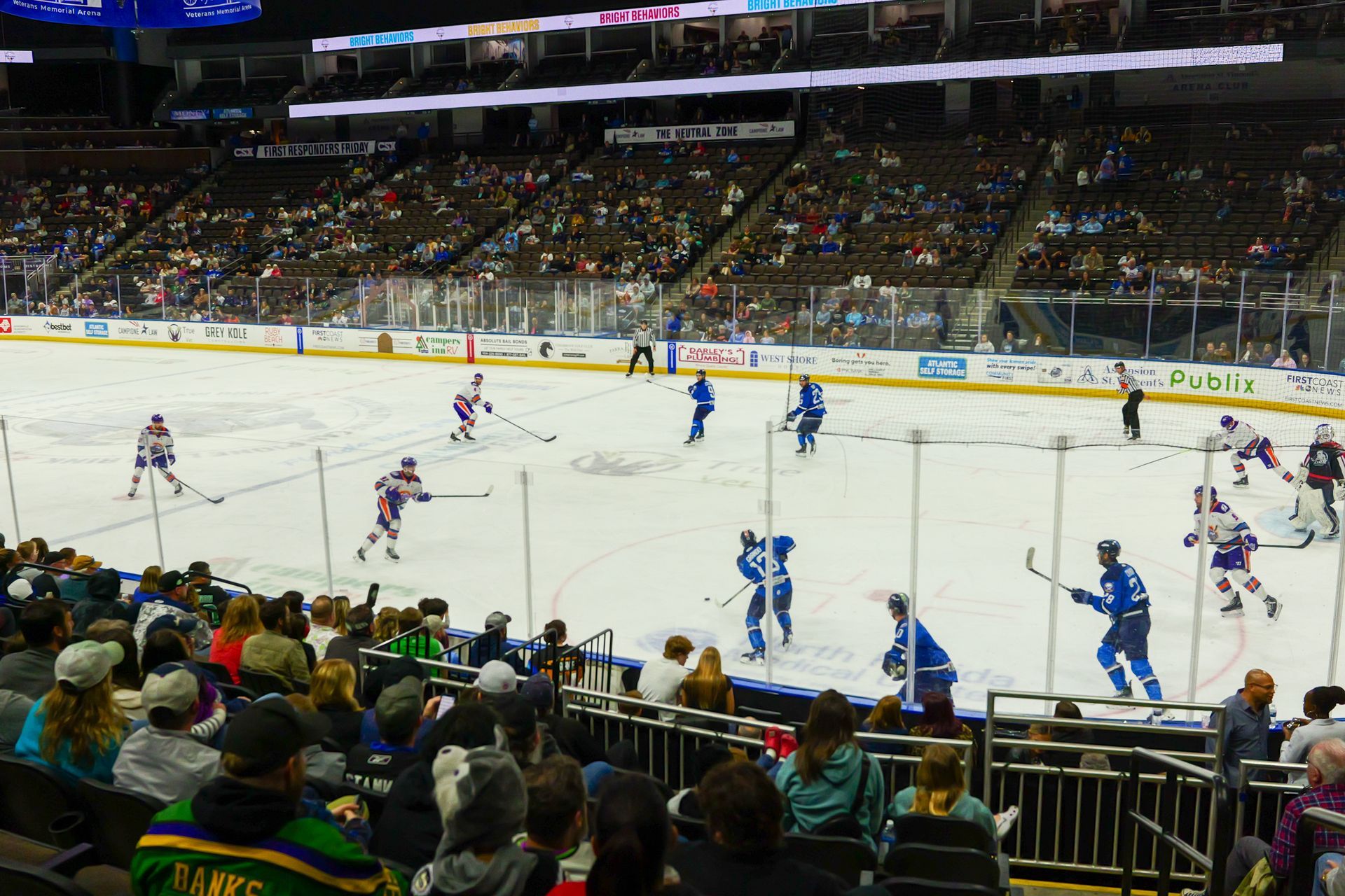 A crowd of people are watching a hockey game in a stadium.