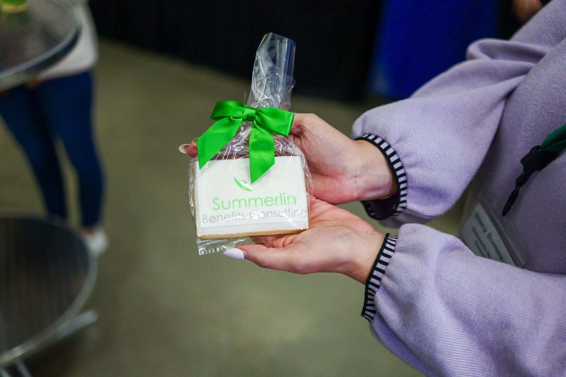 A person is holding a cookie in a plastic bag with a green bow.