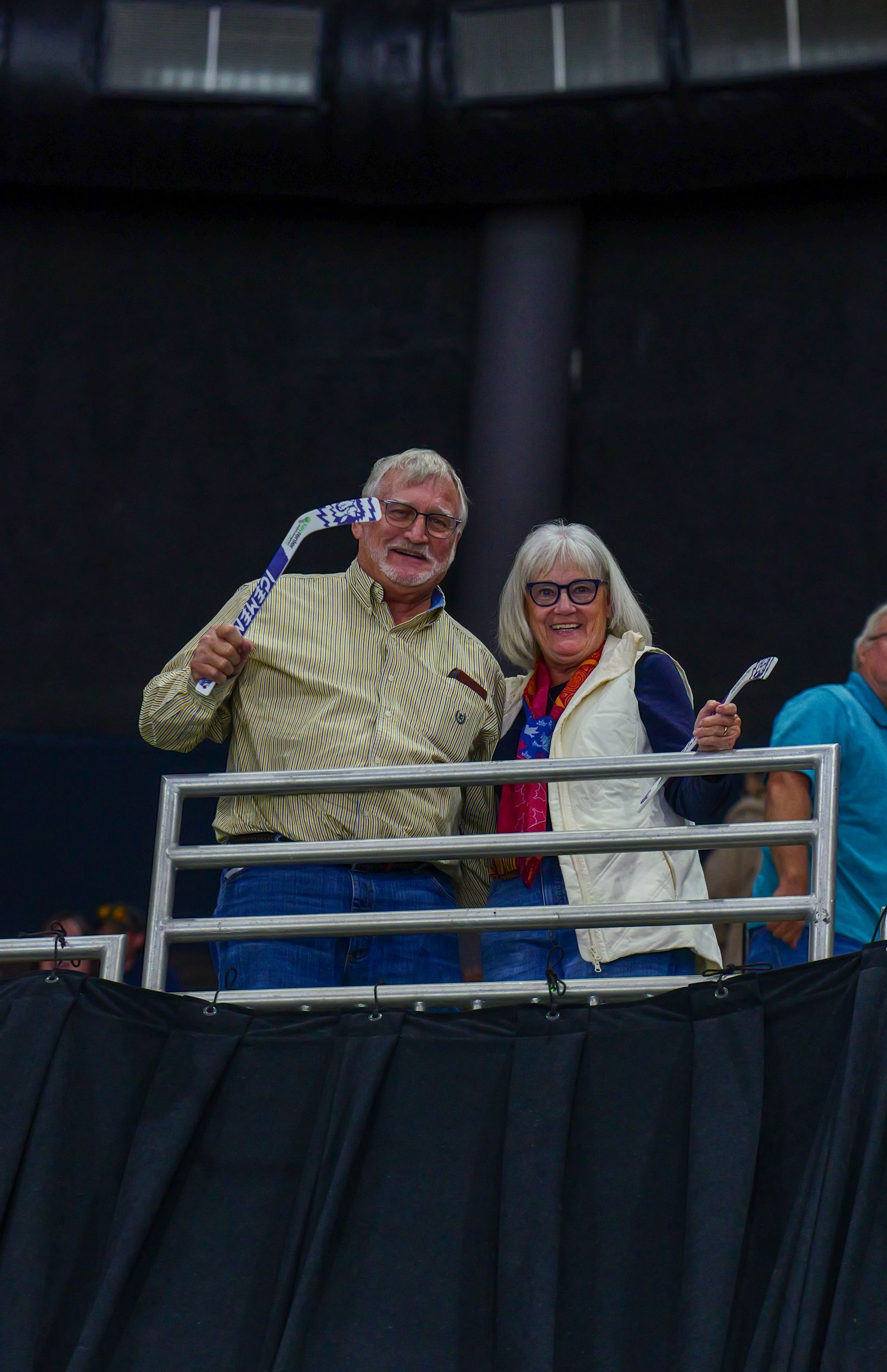 A man and a woman are standing behind a fence holding flags.