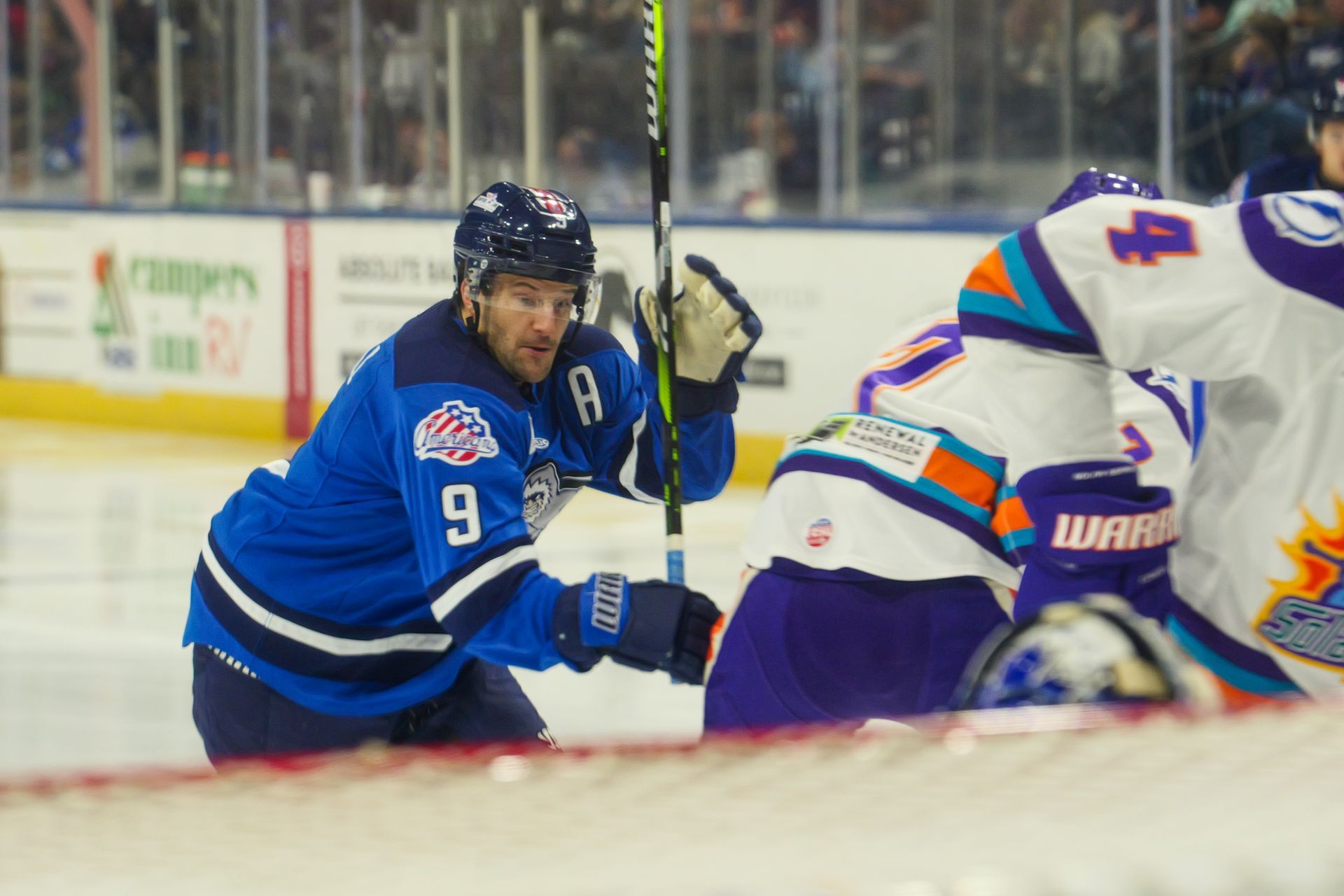 A hockey player with the number 9 on his jersey is holding a hockey stick.