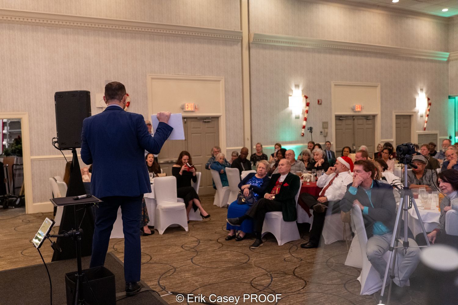 A man is standing in front of a crowd of people in a large room.
