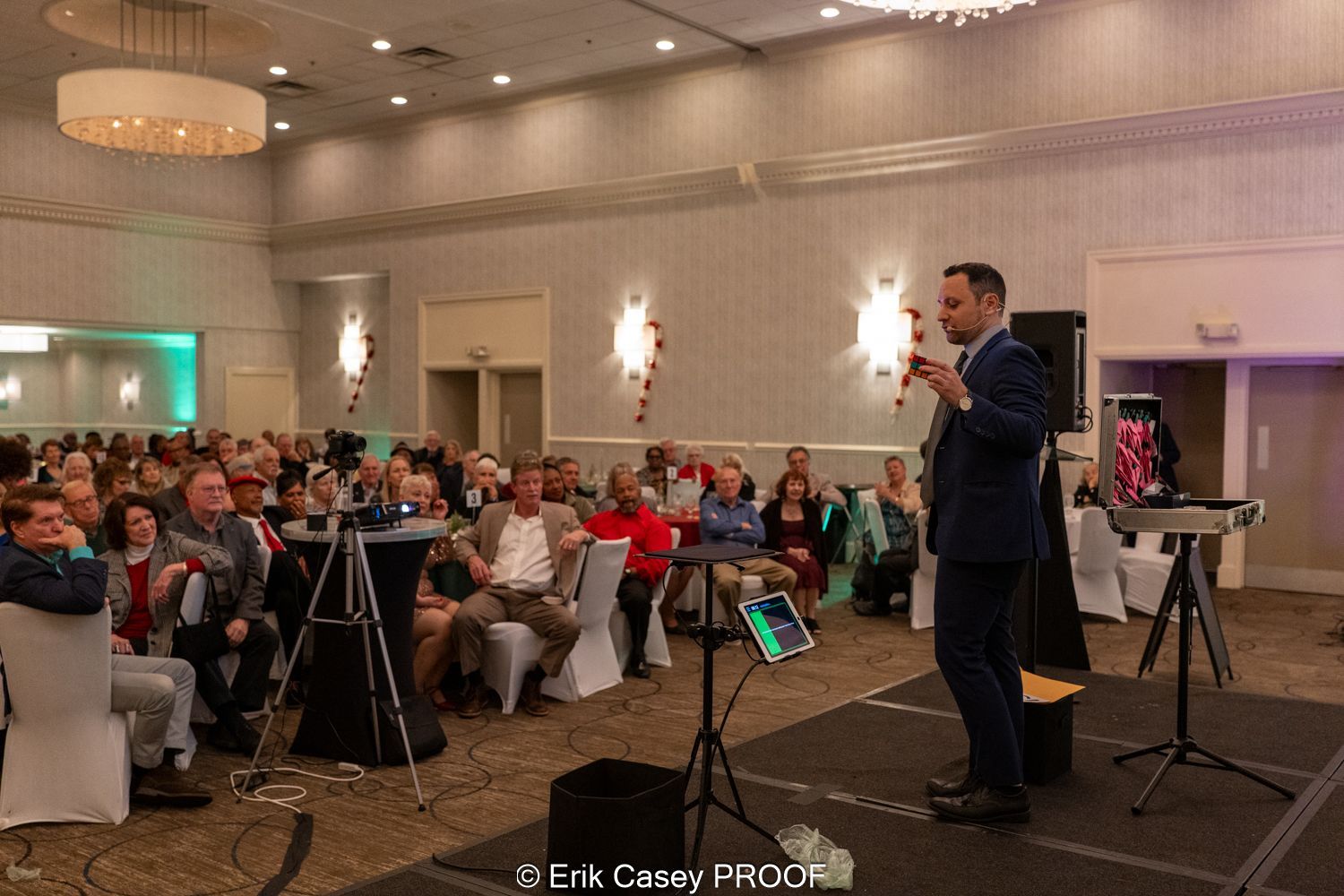 A man is standing on a stage in front of a crowd of people.