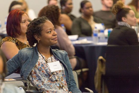 a man with dreadlocks is sitting next to a woman holding a styrofoam container .