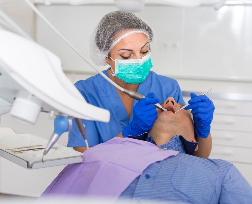 Une dentiste examine les dents d'un homme dans un cabinet dentaire.