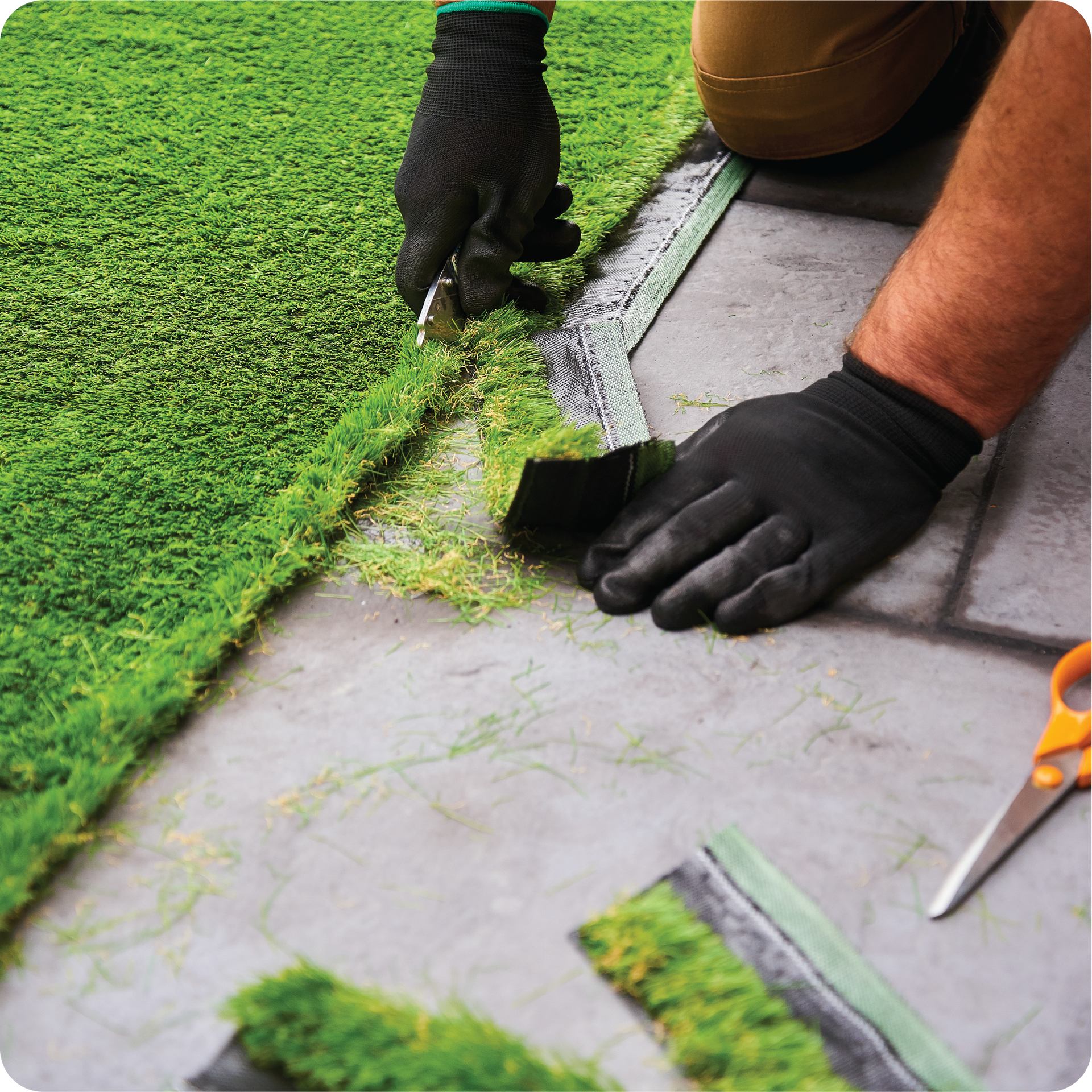 A person is cutting a piece of artificial grass with scissors