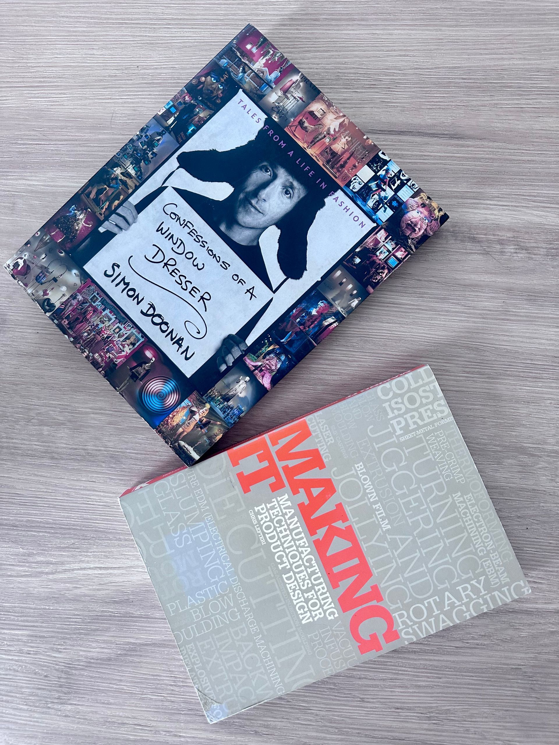 Two photo books on a wooden surface, one floral with a portrait, one gray with red “MALKIN” text.