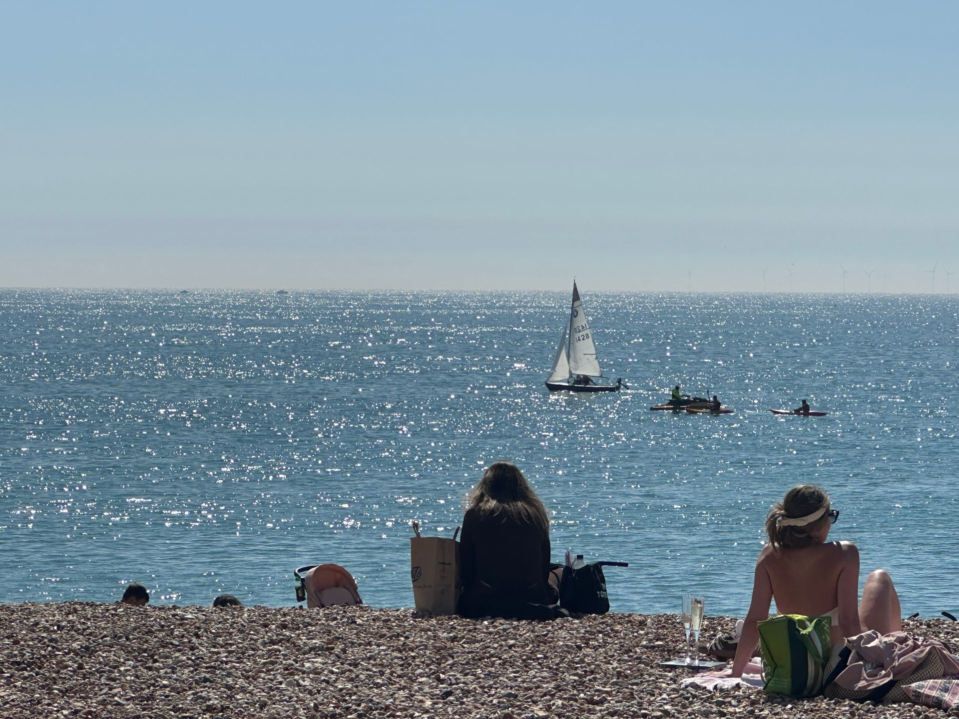 Two people are sitting on a beach looking at the ocean.