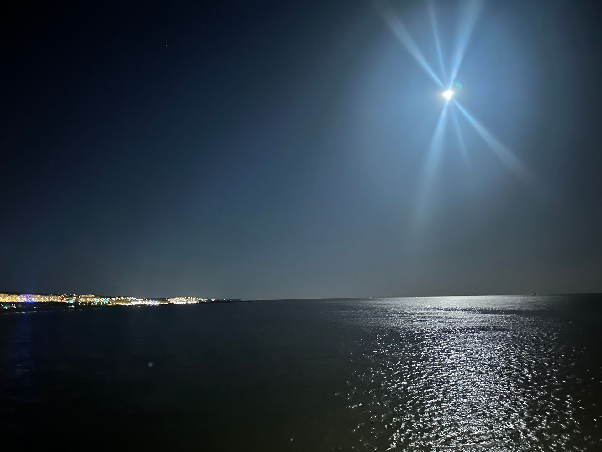 A full moon shines brightly over a body of water