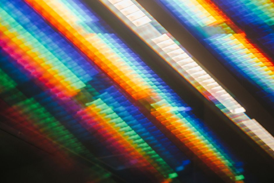 Abstract diagonal rainbow light bands and white reflections across a dark background
