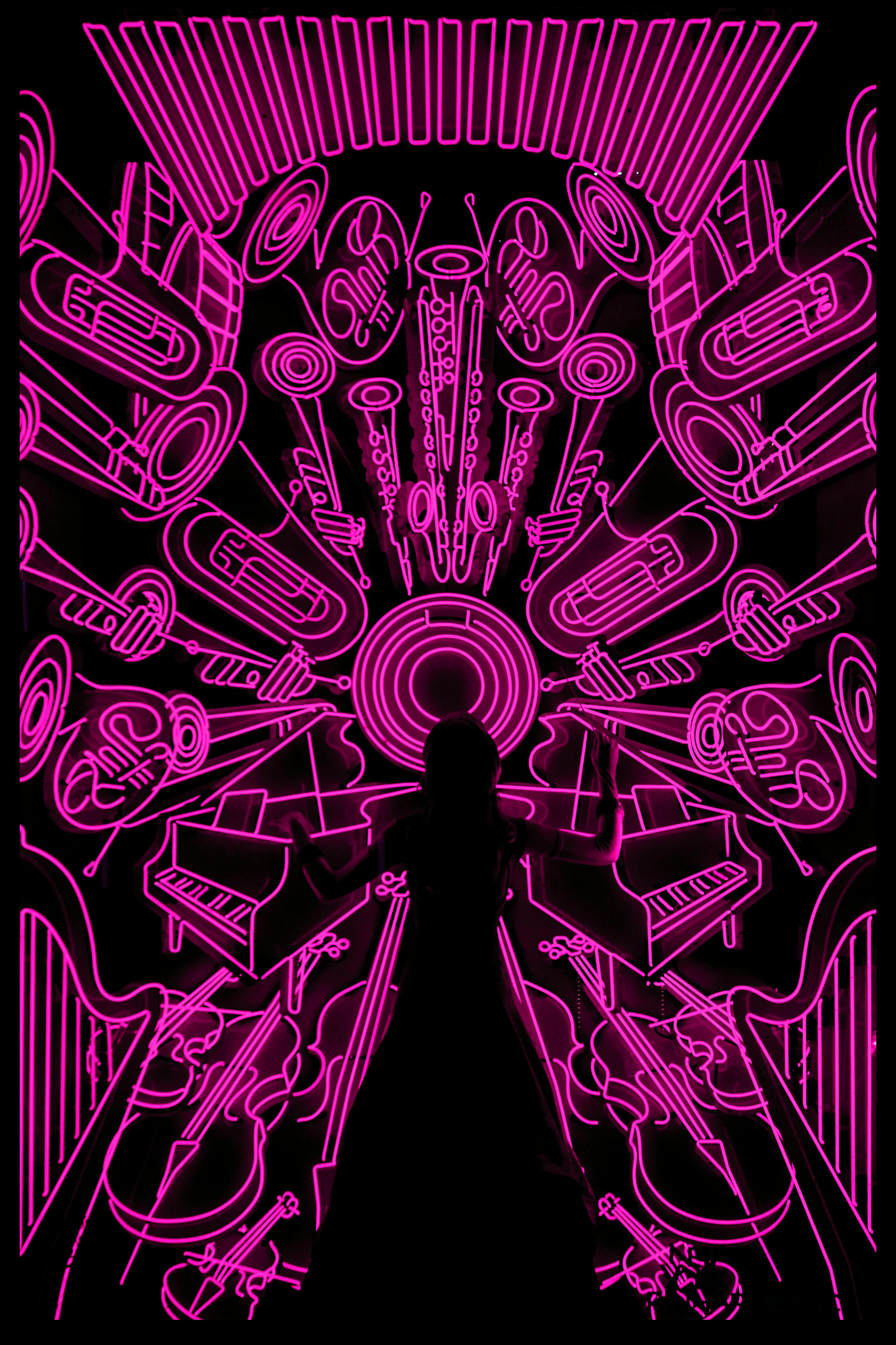 Neon pink symmetrical sci-fi abstract with a central silhouette and radiating mechanical shapes on black background