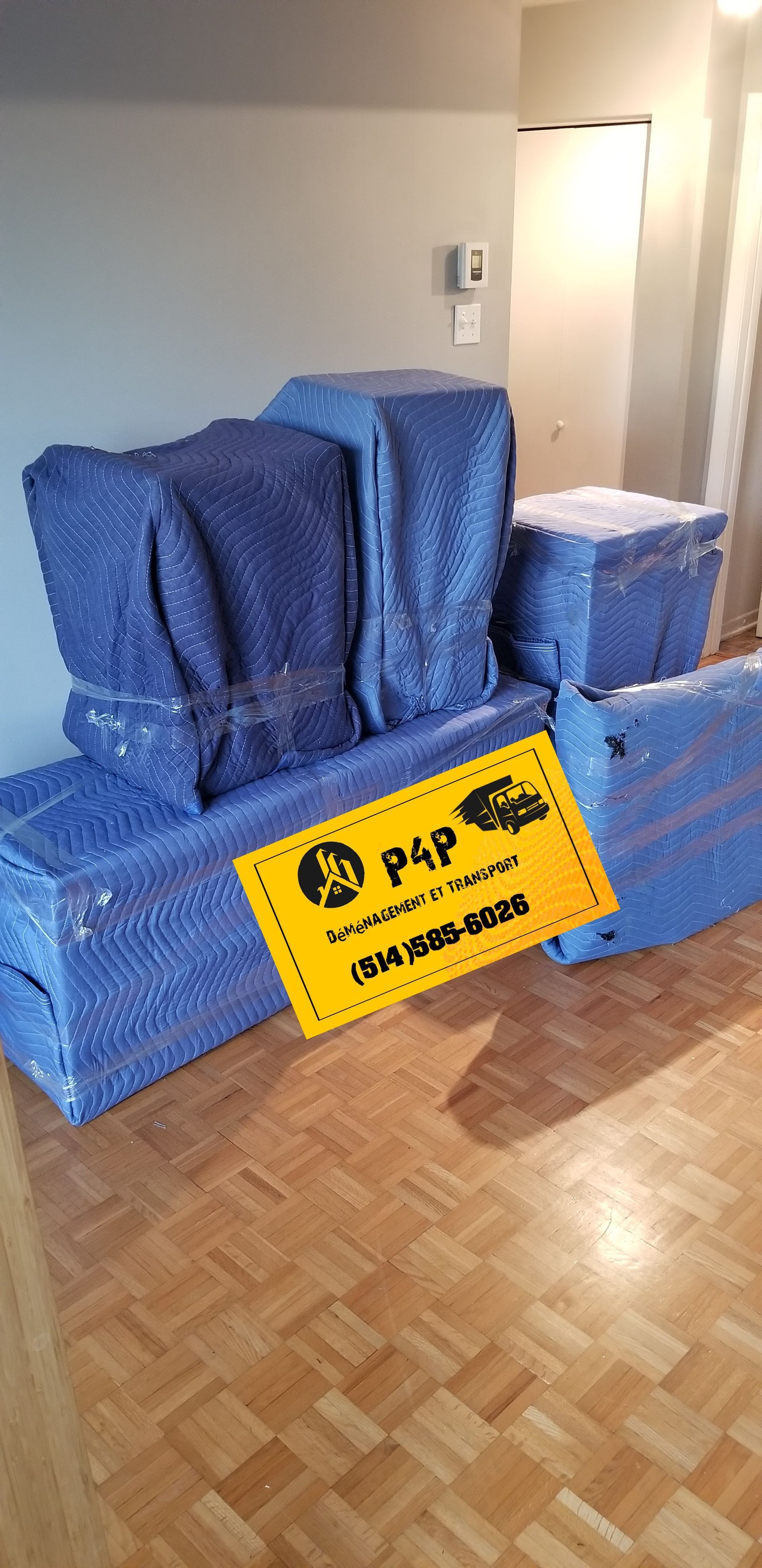 A living room filled with boxes wrapped in blue plastic and a sign.