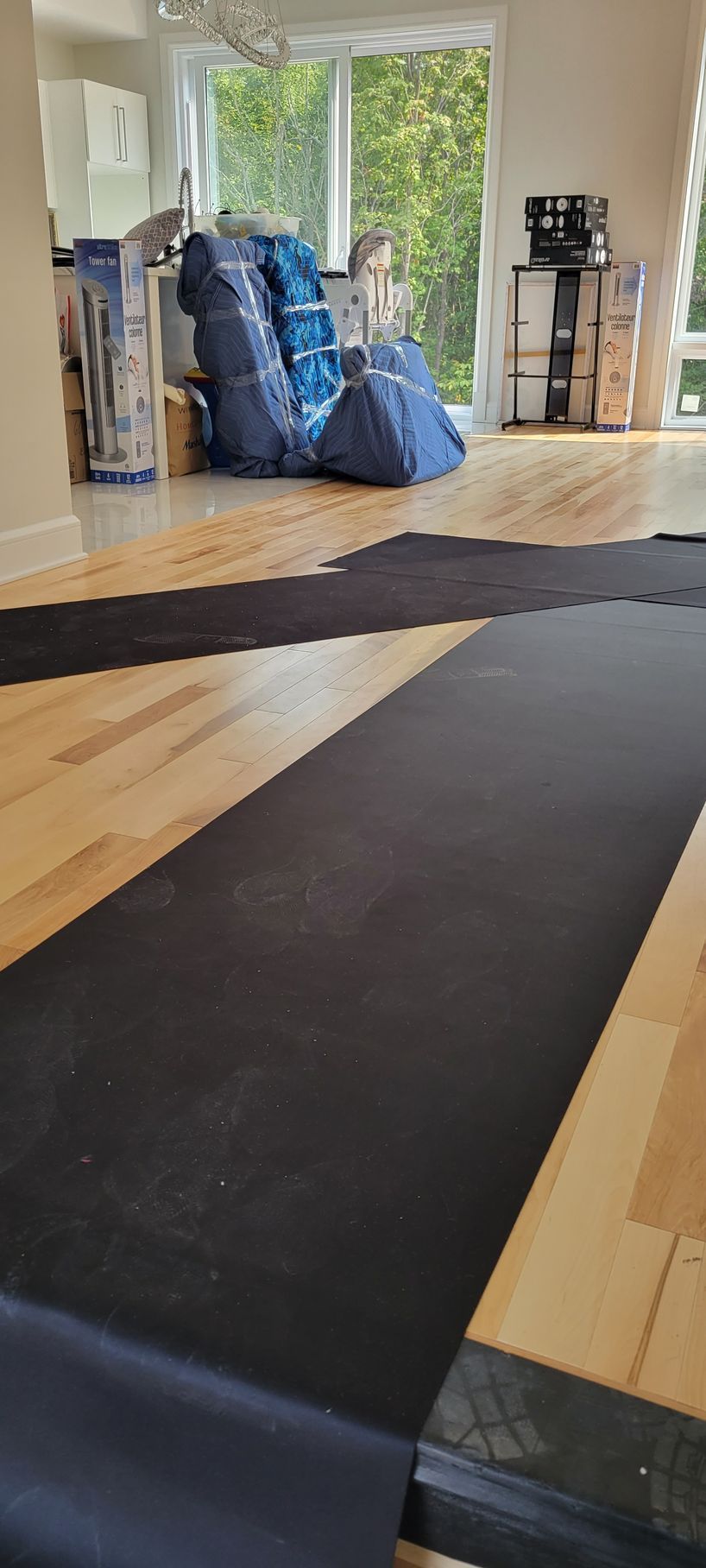 A living room with wooden floors and a black rug on the floor.