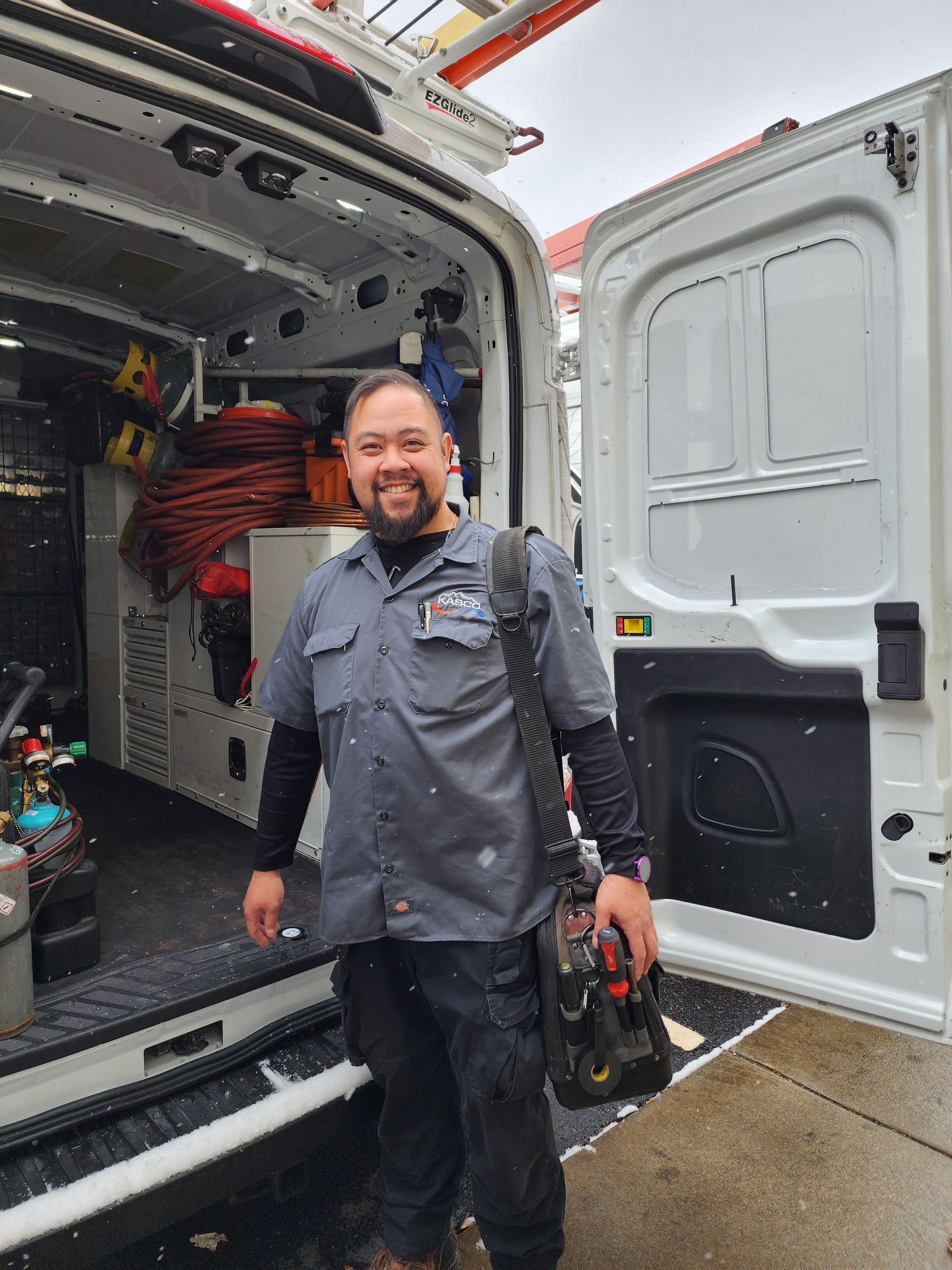 A man is standing in front of a van with the door open.