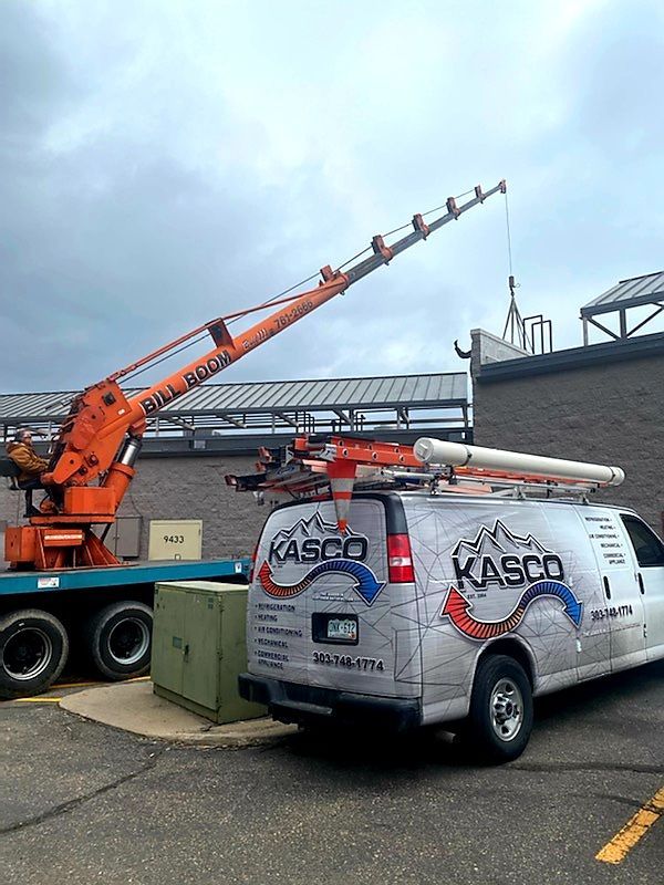 A kasco van is parked in front of a building with a crane on top of it.