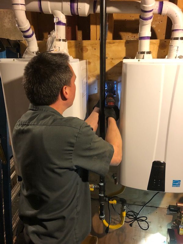 A man is working on a water heater in a basement