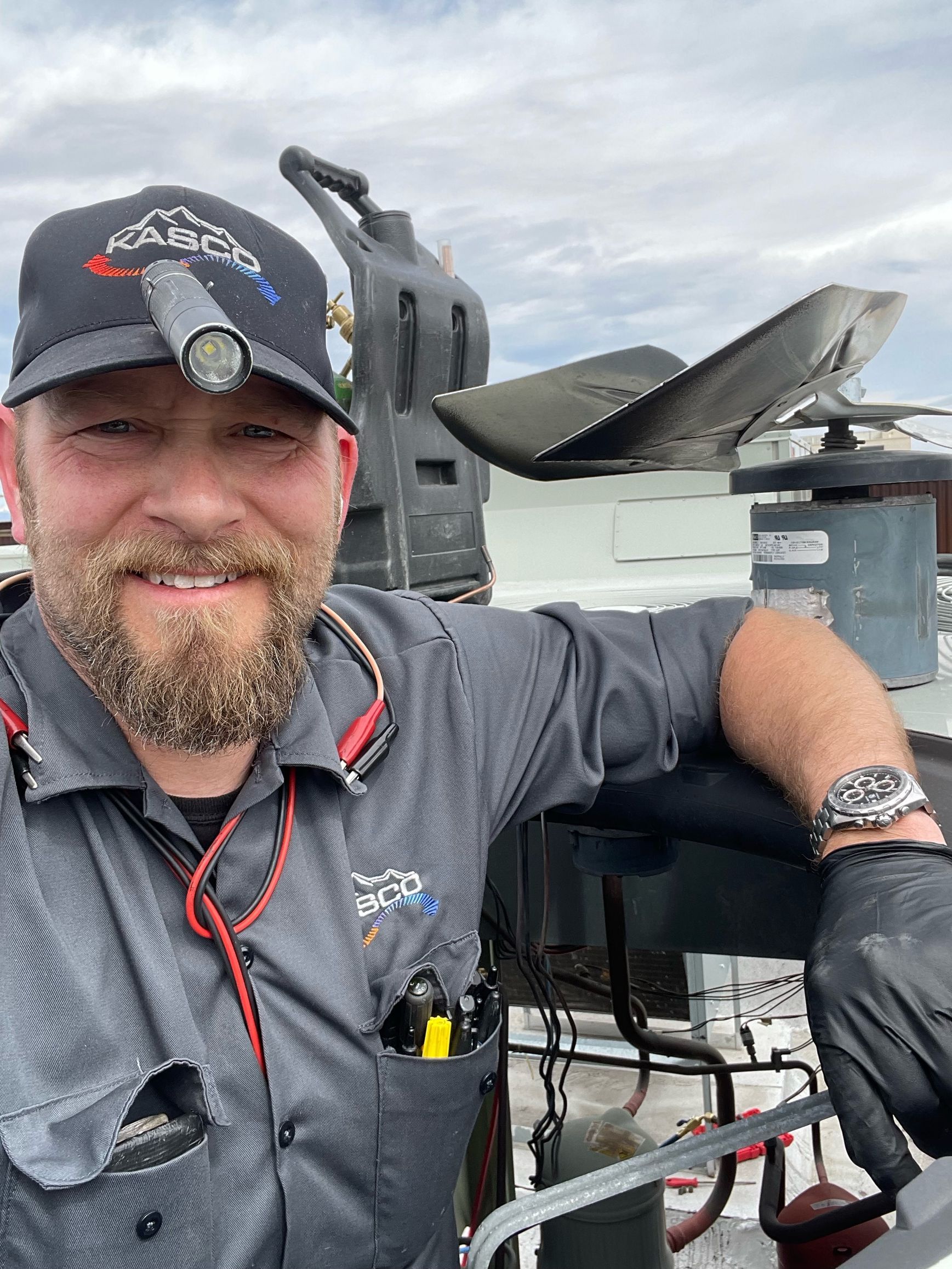 A man with a beard wearing a hat and gloves is standing next to a boat.
