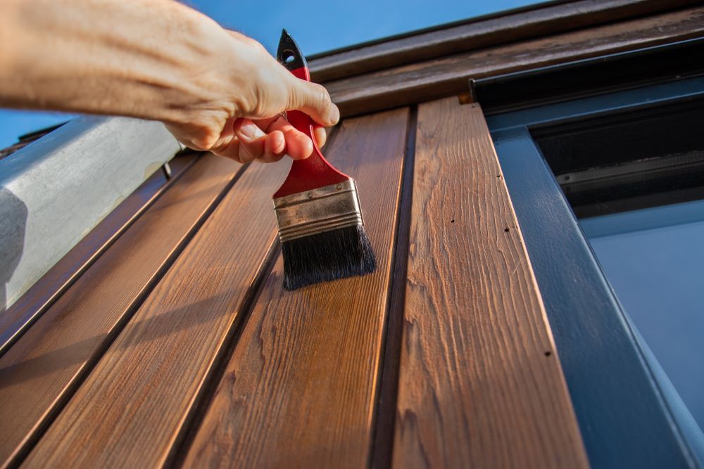A Person Is Painting a Wooden Wall with A Brush — Central West Paint Supplies in Dubbo, NSW