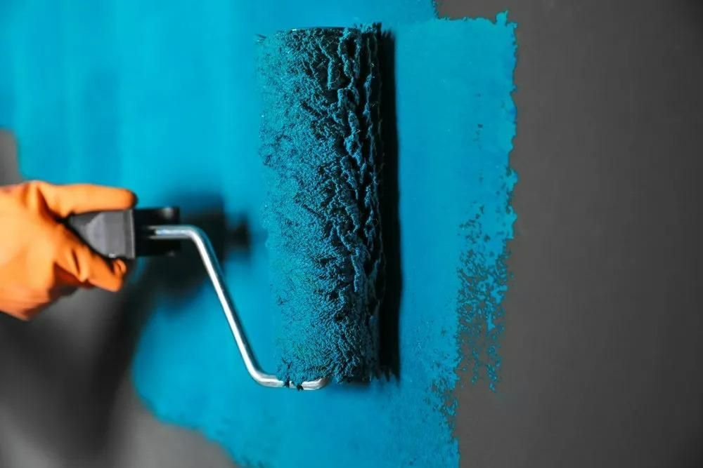 Someone is rolling blue paint on a black background — Central West Paint Supplies in Dubbo, NSW