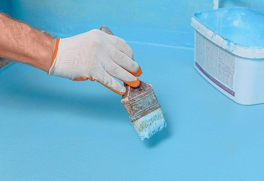 A Person Is Painting a Blue Surface — Central West Paint Supplies in Dubbo, NSW