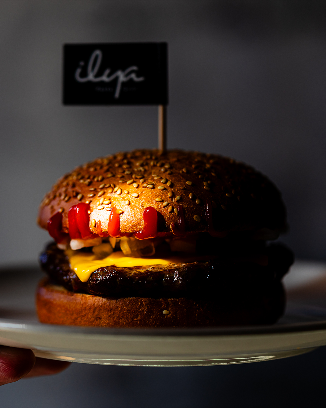 Close-up van een hamburger op een bord met het logo van het restaurant.