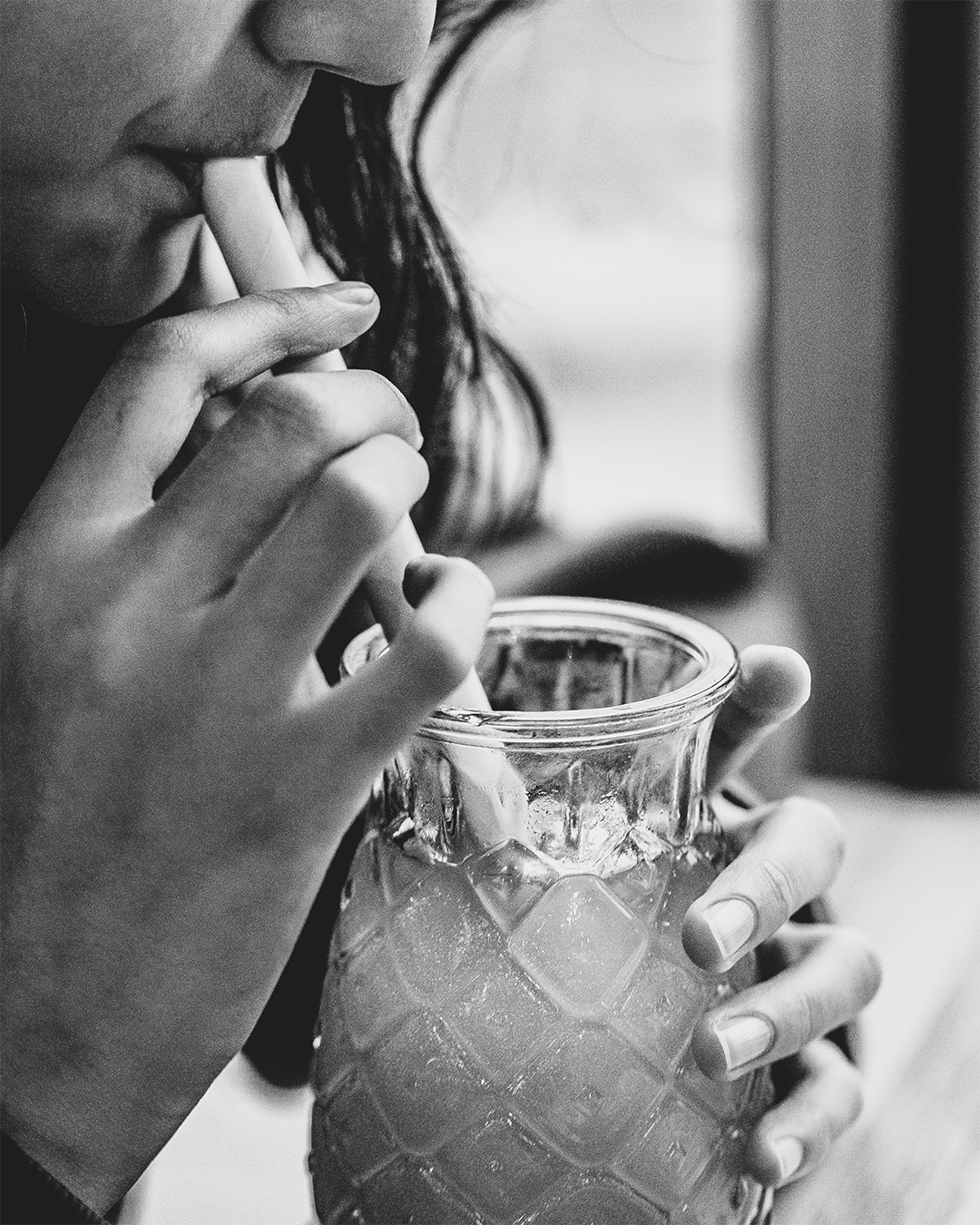 Vrouw drinkt een drankje met een rietje uit een glas met een patroon.
