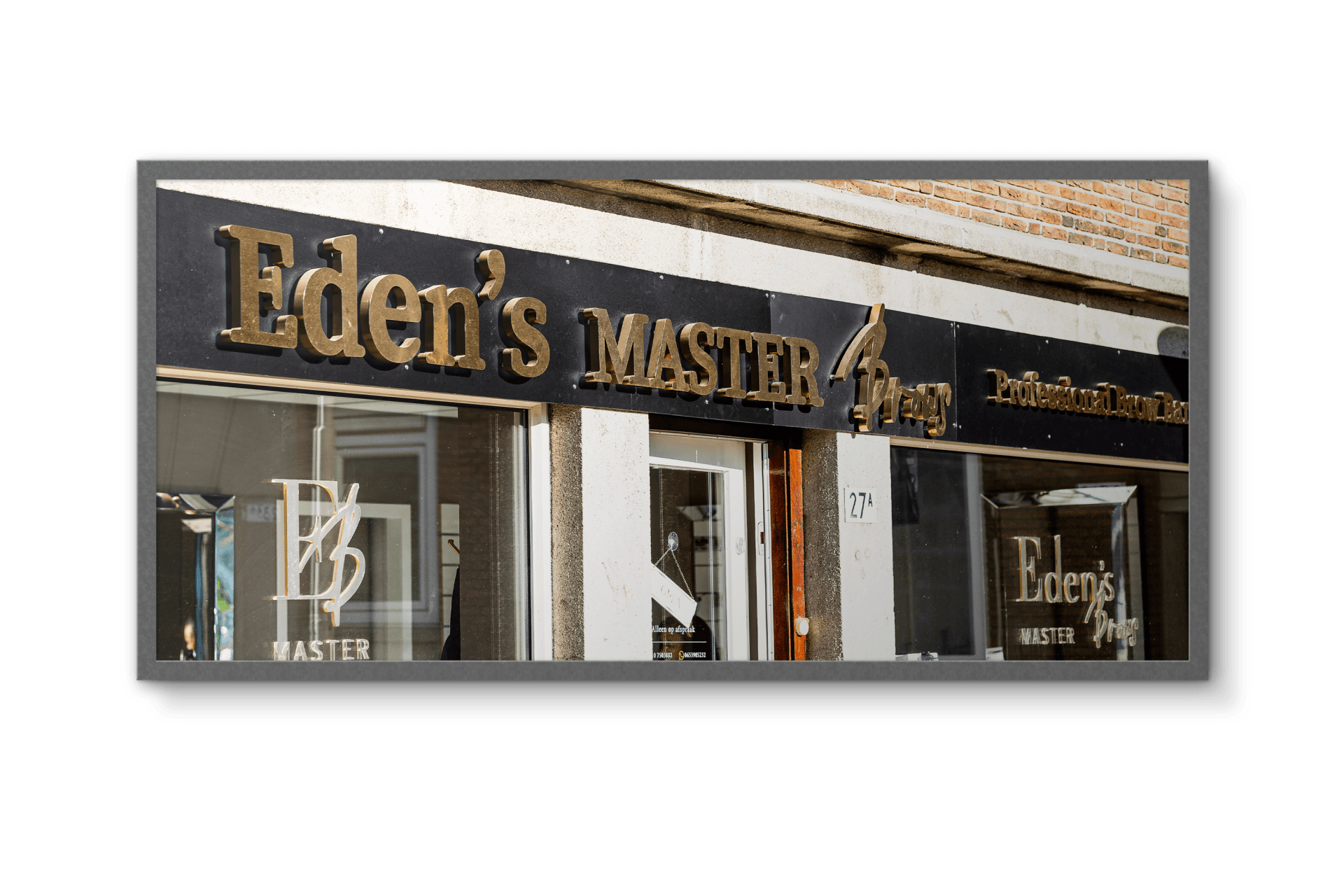 De gevel van Eden's Master Barbershop met gouden letters, ramen en een zwarte achtergrond.