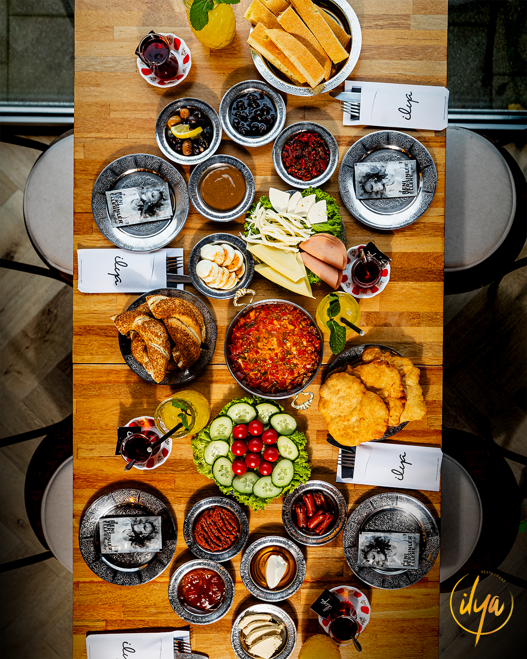 Bovenaanzicht van een Turks ontbijt dat op een houten tafel is uitgestald met diverse gerechten en drankjes.