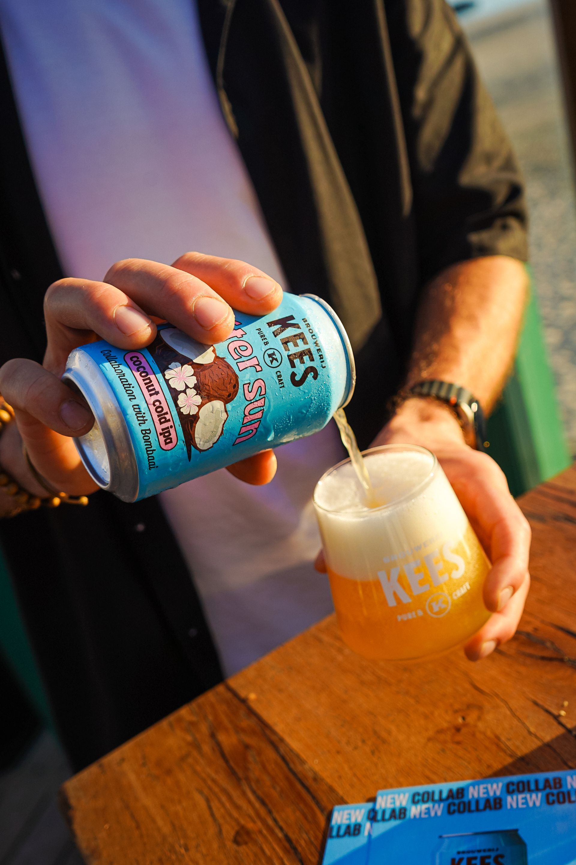 Iemand schenkt bier uit een blikje Kees in een glas; zowel het blikje als het glas zijn voorzien van het Kees-logo.