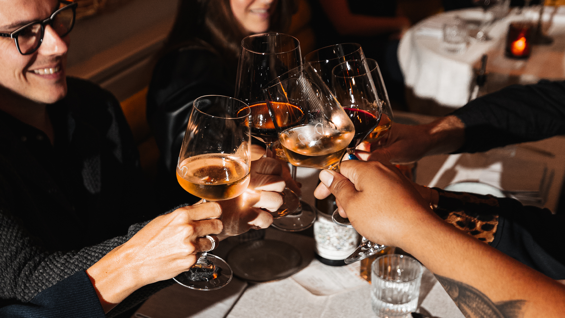 A group of people are sitting at a table toasting with wine glasses.