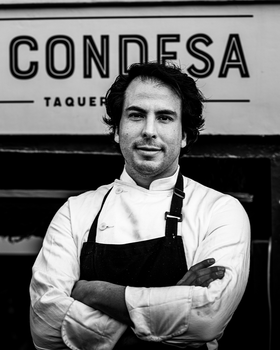 De chef-kok staat met gekruiste armen voor het bord