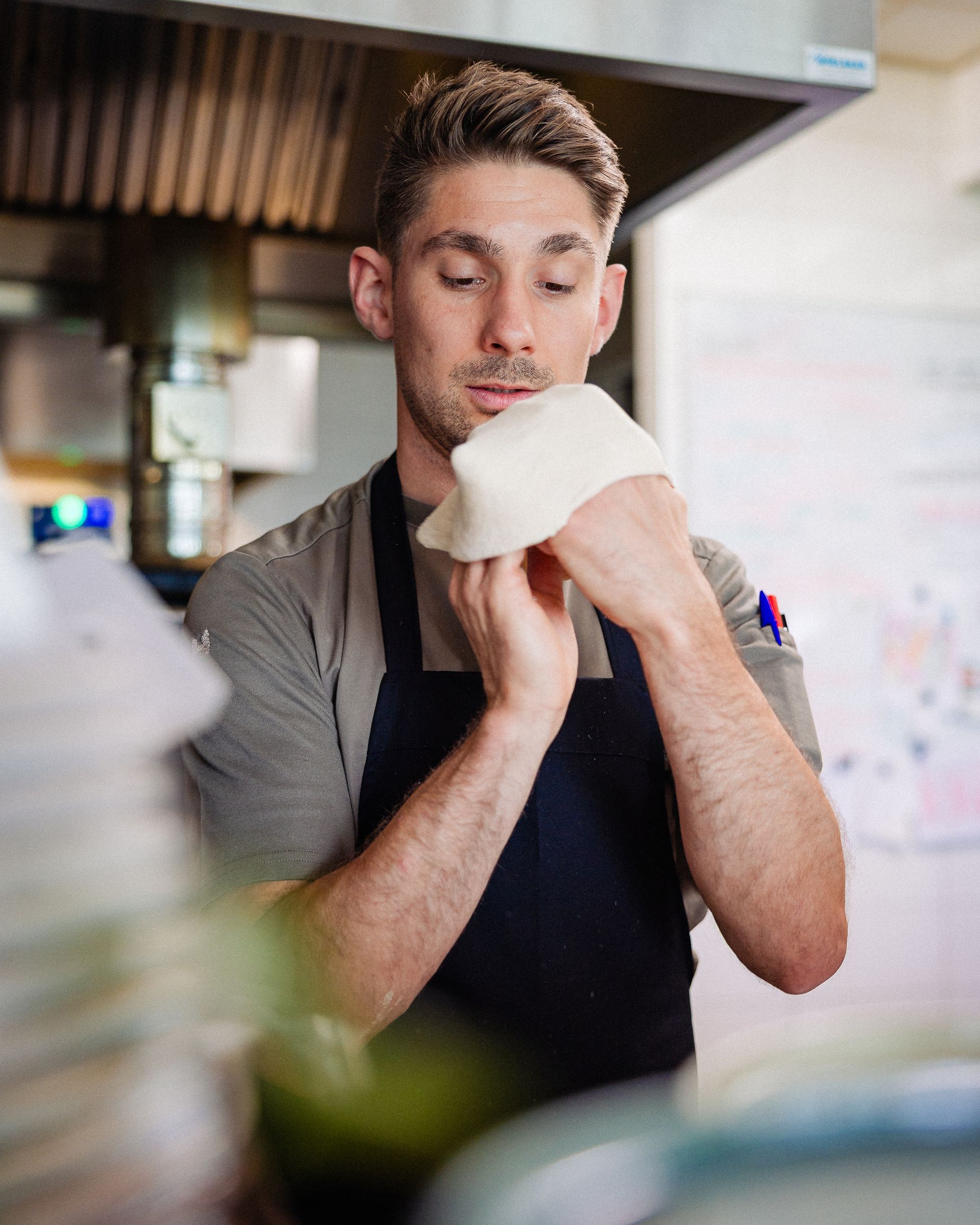 Een chef-kok houdt deeg vast in de keuken en bekijkt het met een geconcentreerde blik.