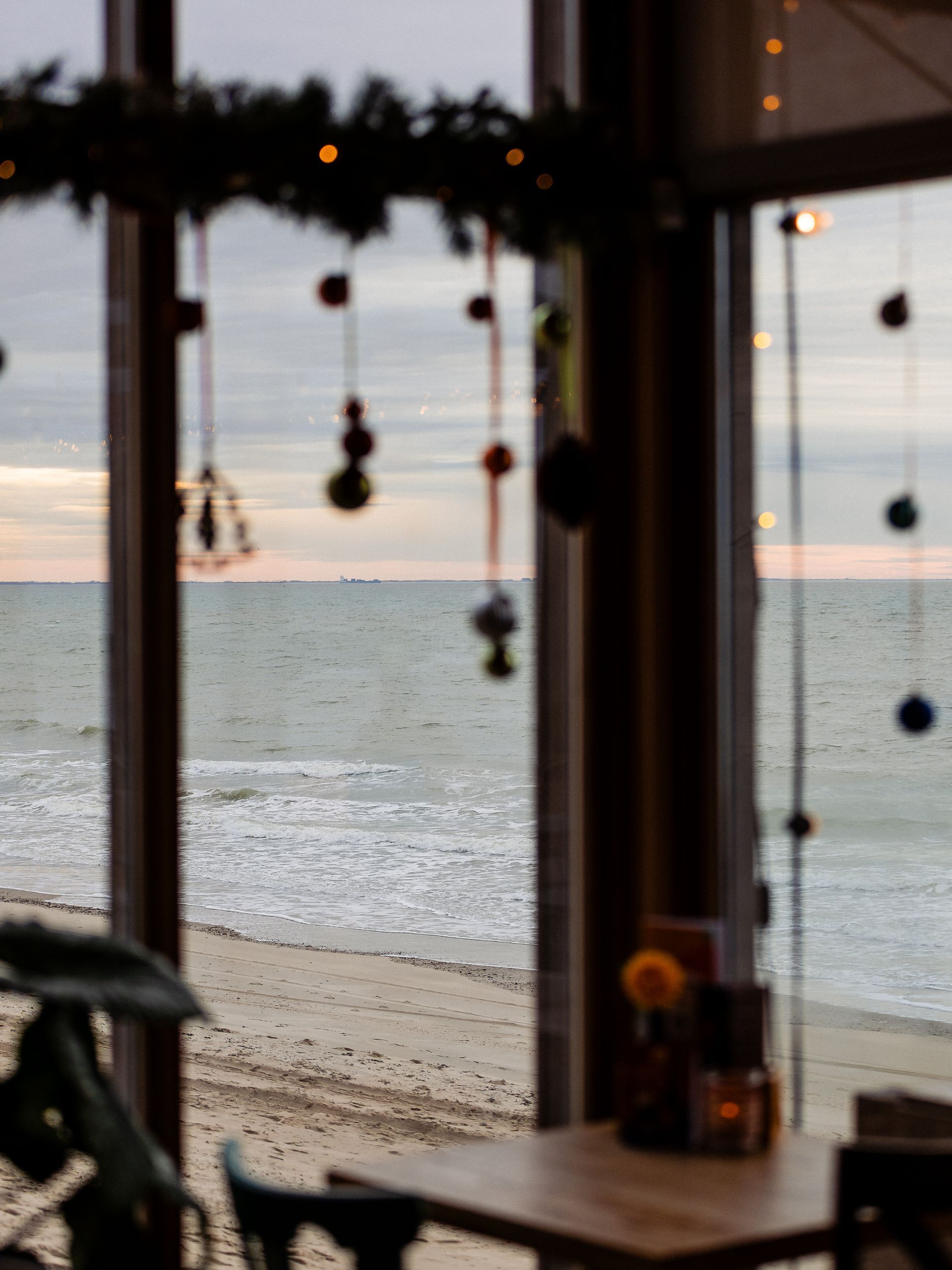 Uitzicht op een strand en de oceaan door een raam versierd met ornamenten.