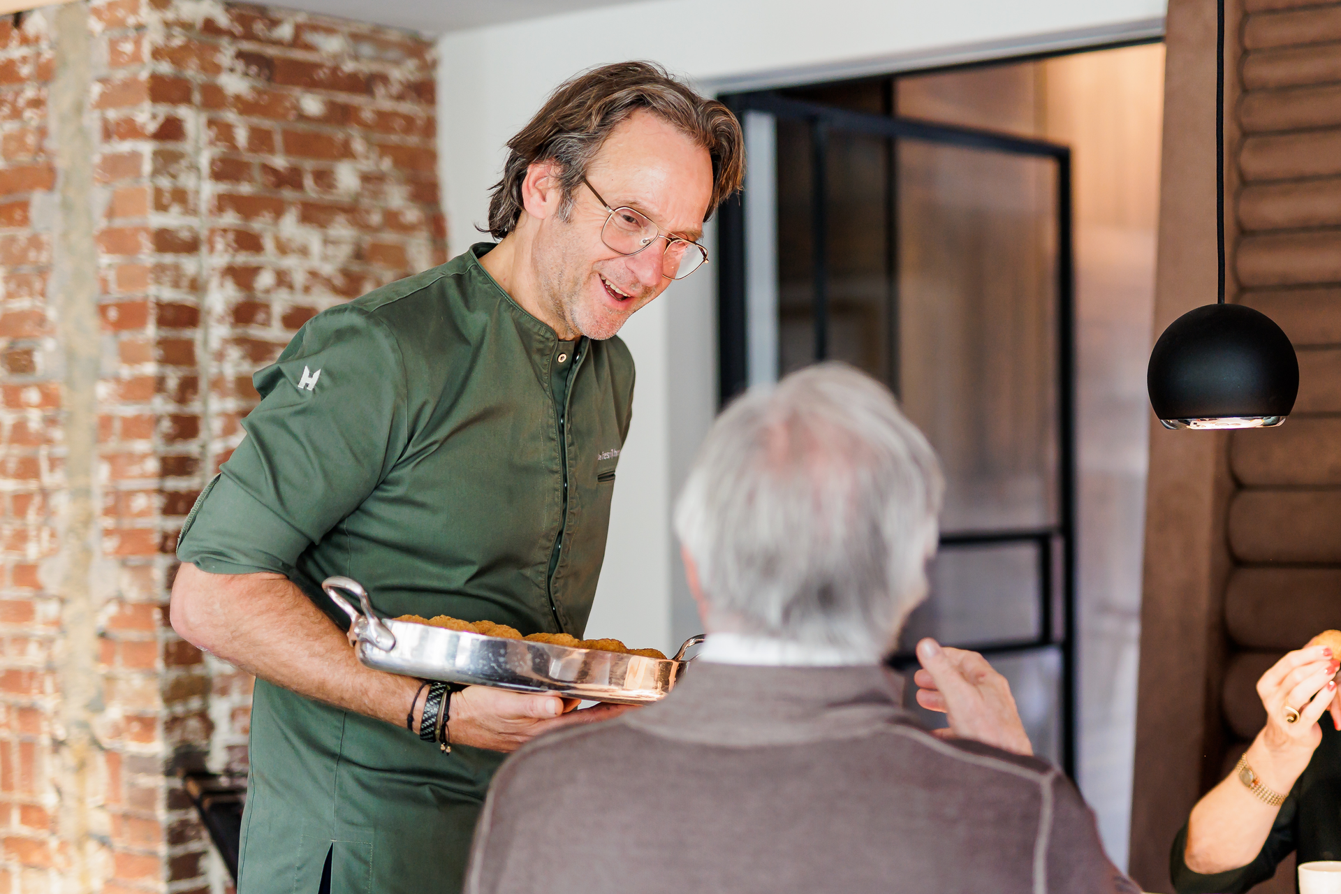 Chef Dick Middelweerd aan tafel bij gasten in zijn restaurant De Treeswijkhoeve.
