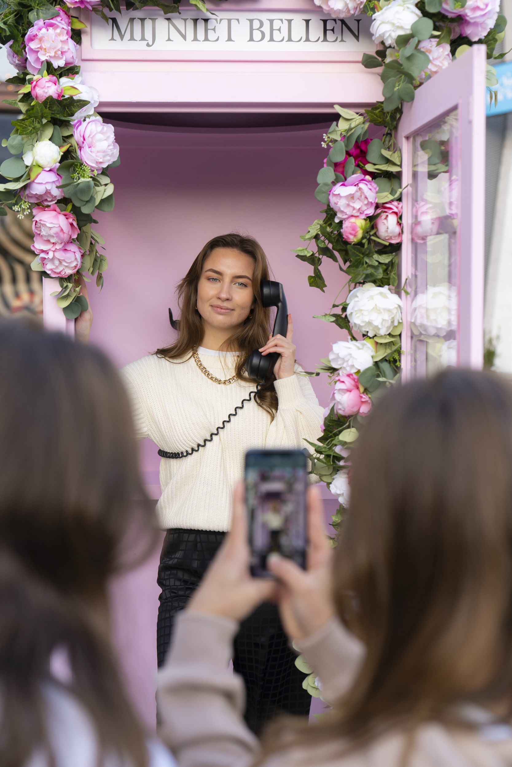 Een vrouw maakt een foto van zichzelf in een roze telefooncel.