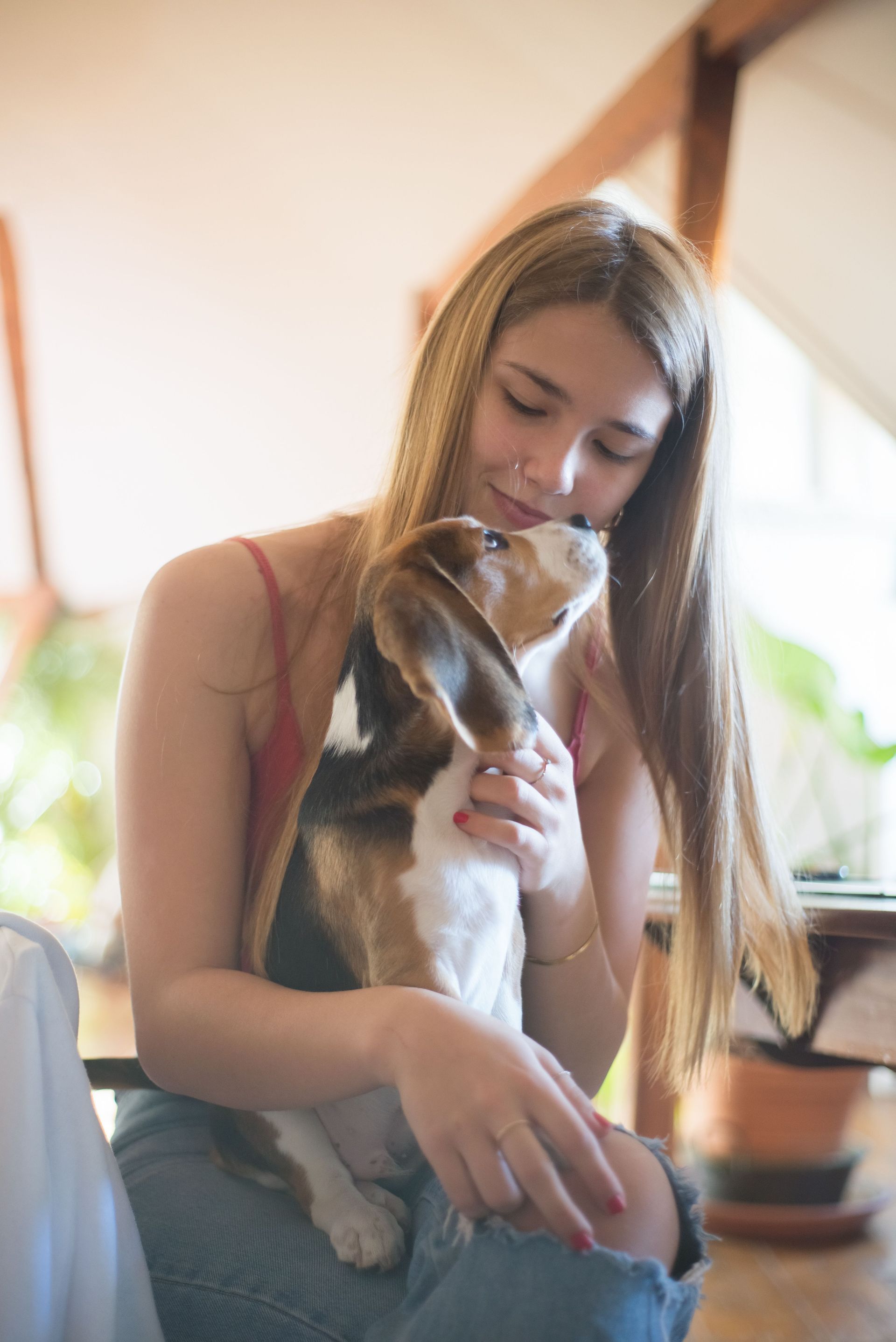 Young woman gently holding a cat indoors by a window
