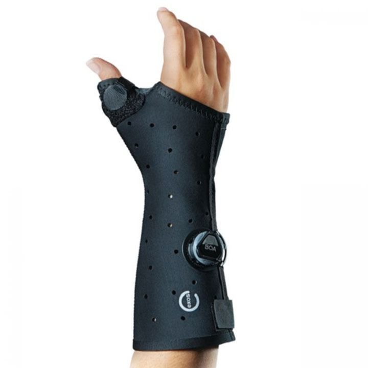 Black wrist brace with thumb support and adjustable straps on a hand.