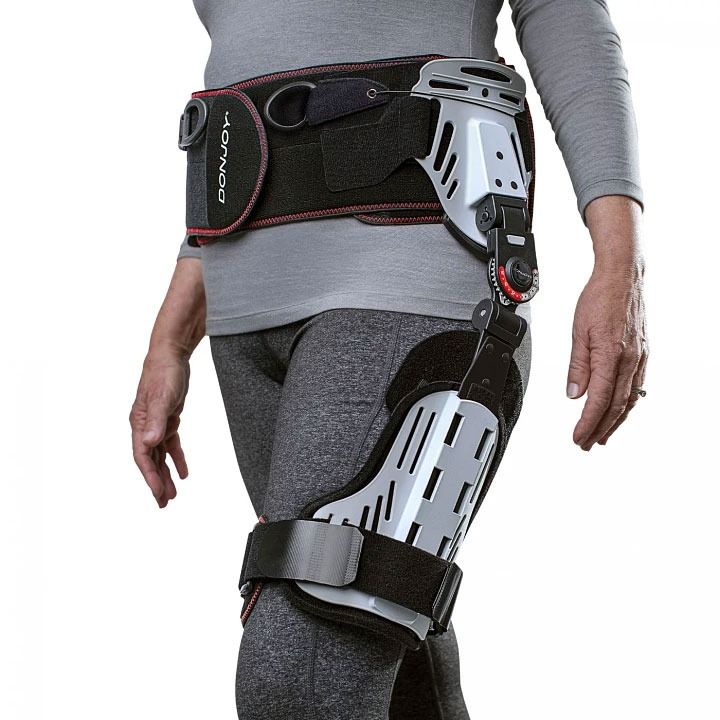 Person wearing a black and gray medical leg brace and hip support harness